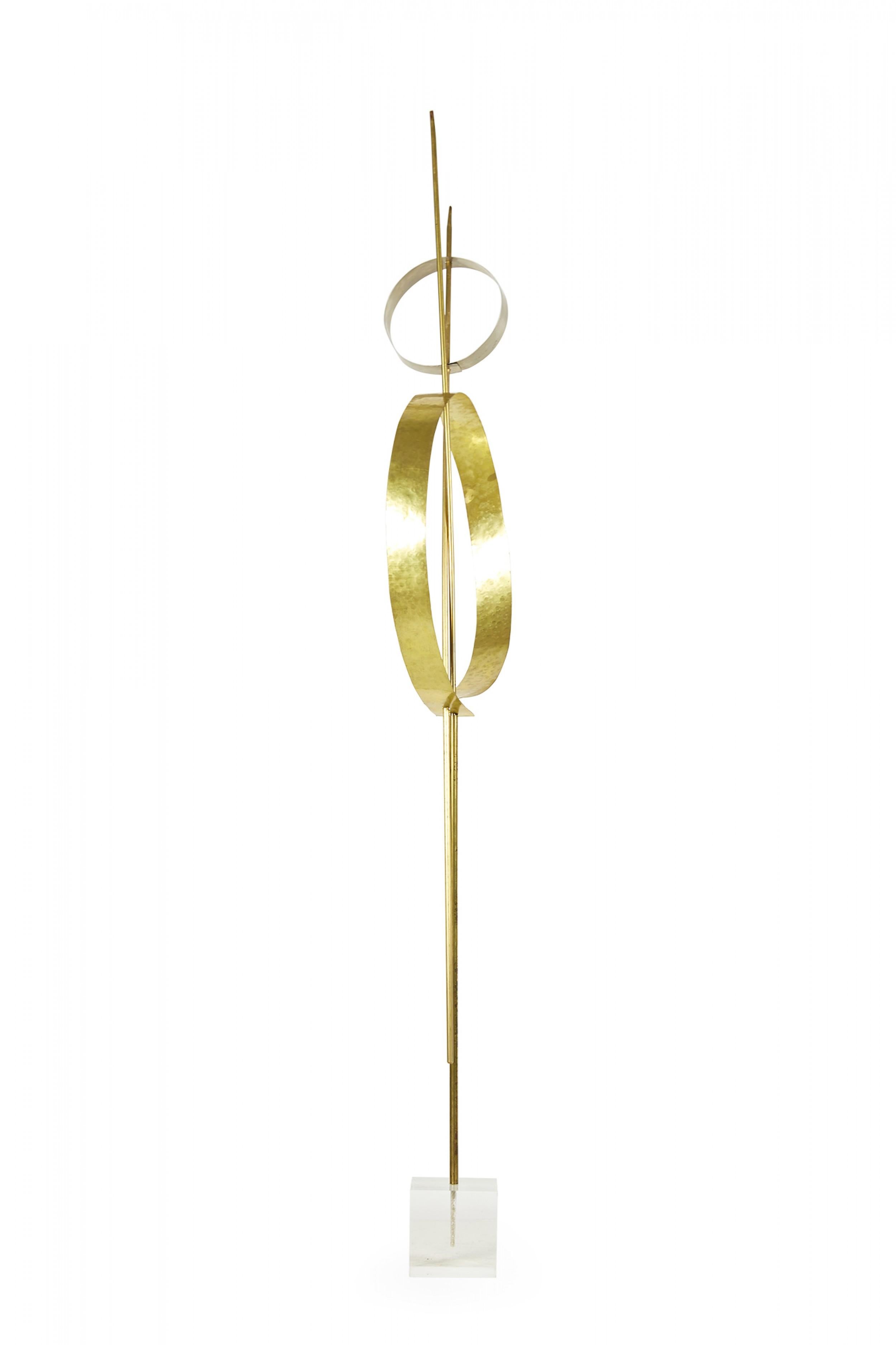 Contemporary abstract sculpture comprised of two nickel and brass circular pieces mounted on two intersecting brass rods, one of which is anchored in a lucite base, titled, 