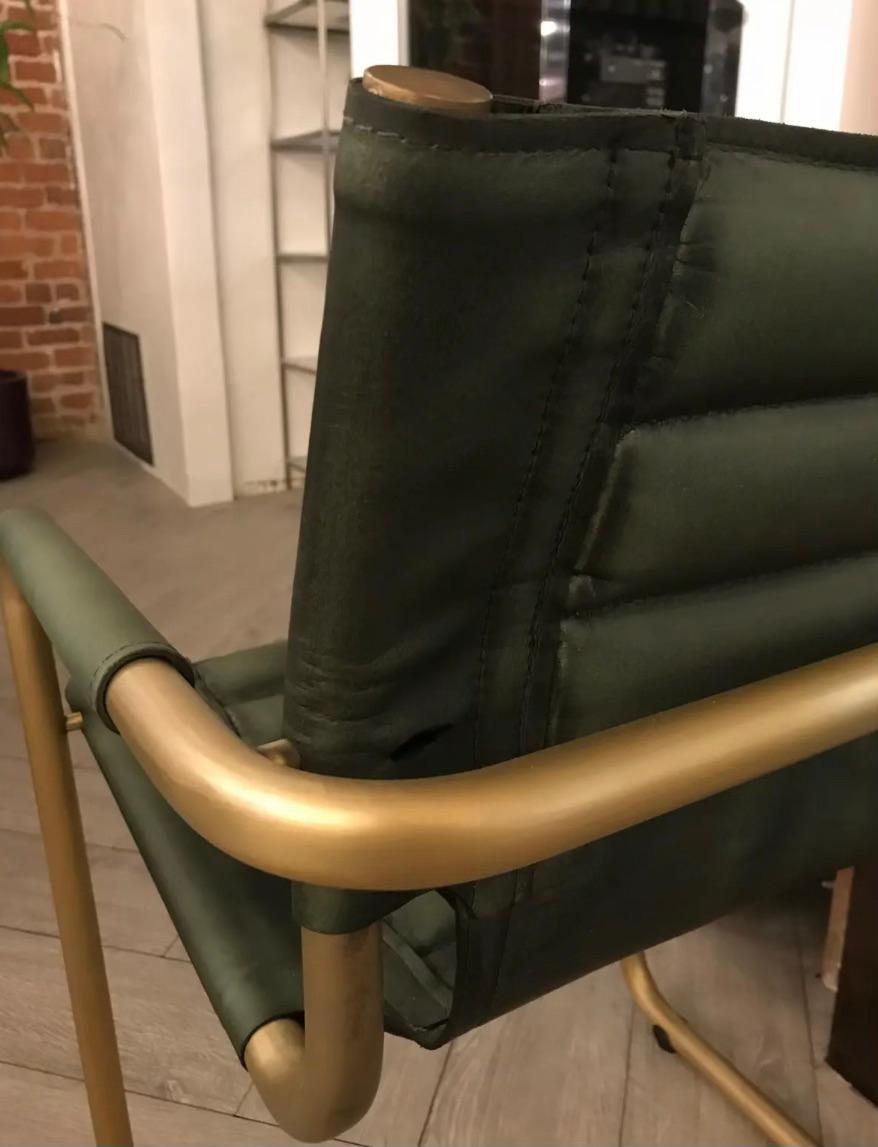 Military green accent chair with attractive curved arms of brass and a leather seat. Bring your surroundings into a cool contemporary feel, while adding character and liveliness with this piece. 