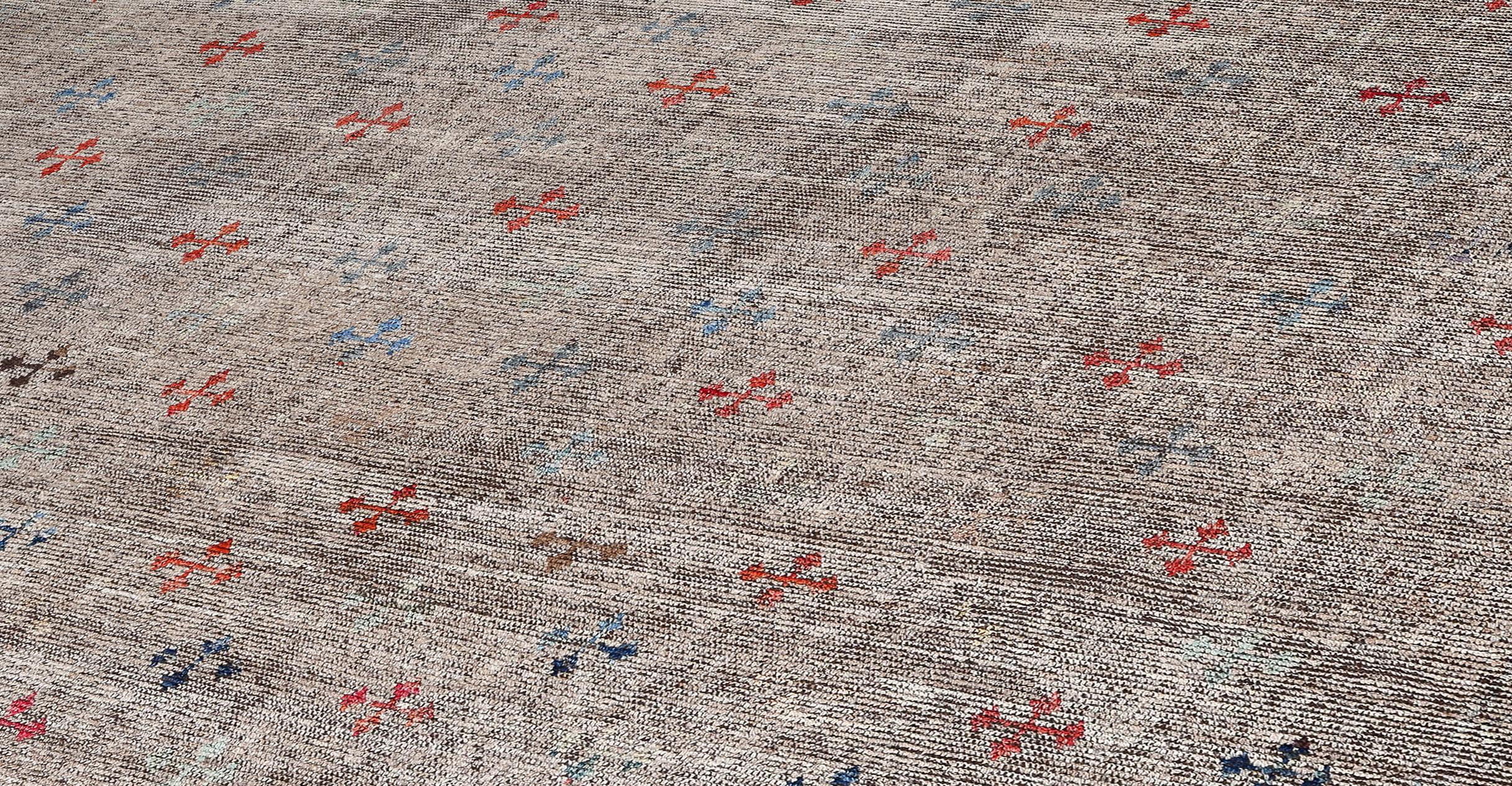 Questo tappeto afgano contemporaneo è tessuto a mano con lana filata a mano e tinto naturalmente con pigmenti vegetali. La sua palette di lana neutra è esaltata da sottili tocchi di colore in piccoli motivi floreali geometrici, disposti in un design