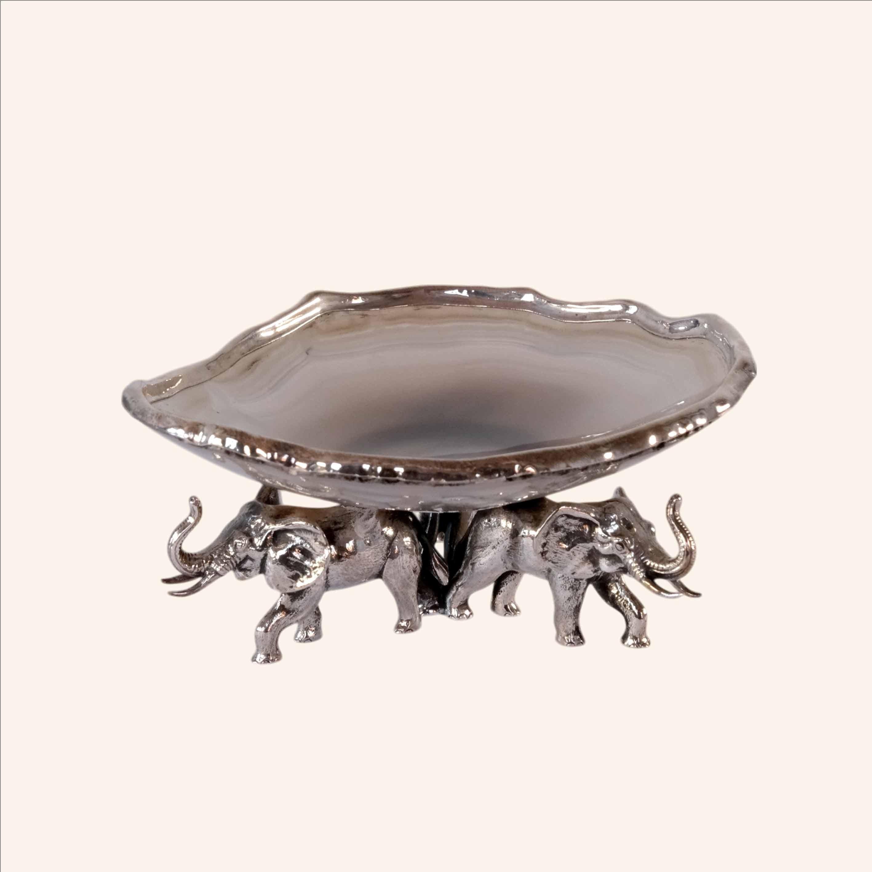 La coupe contemporaine en agate avec base à trois éléphants d'Alcino Silversmith 1902 est une pièce fabriquée à la main en argent 925. 

Cette pièce est fabriquée à la main :  réalisée par une plaque d'argent découpée et collée à la pierre d'agate.