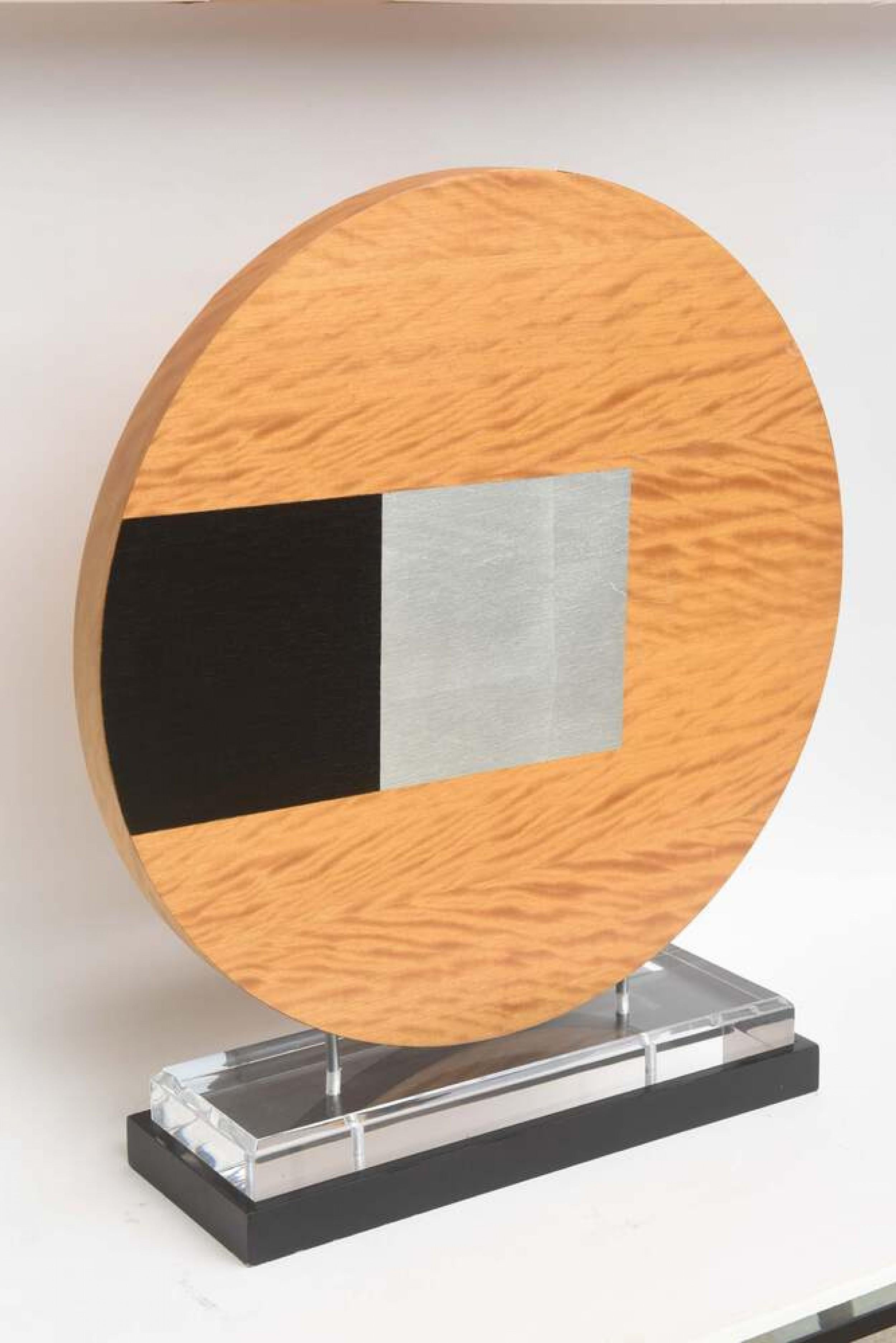 Contemporary American abstract sculpture featuring a wooden desk with geometric black and gray designs, mounted on a rectangular base.