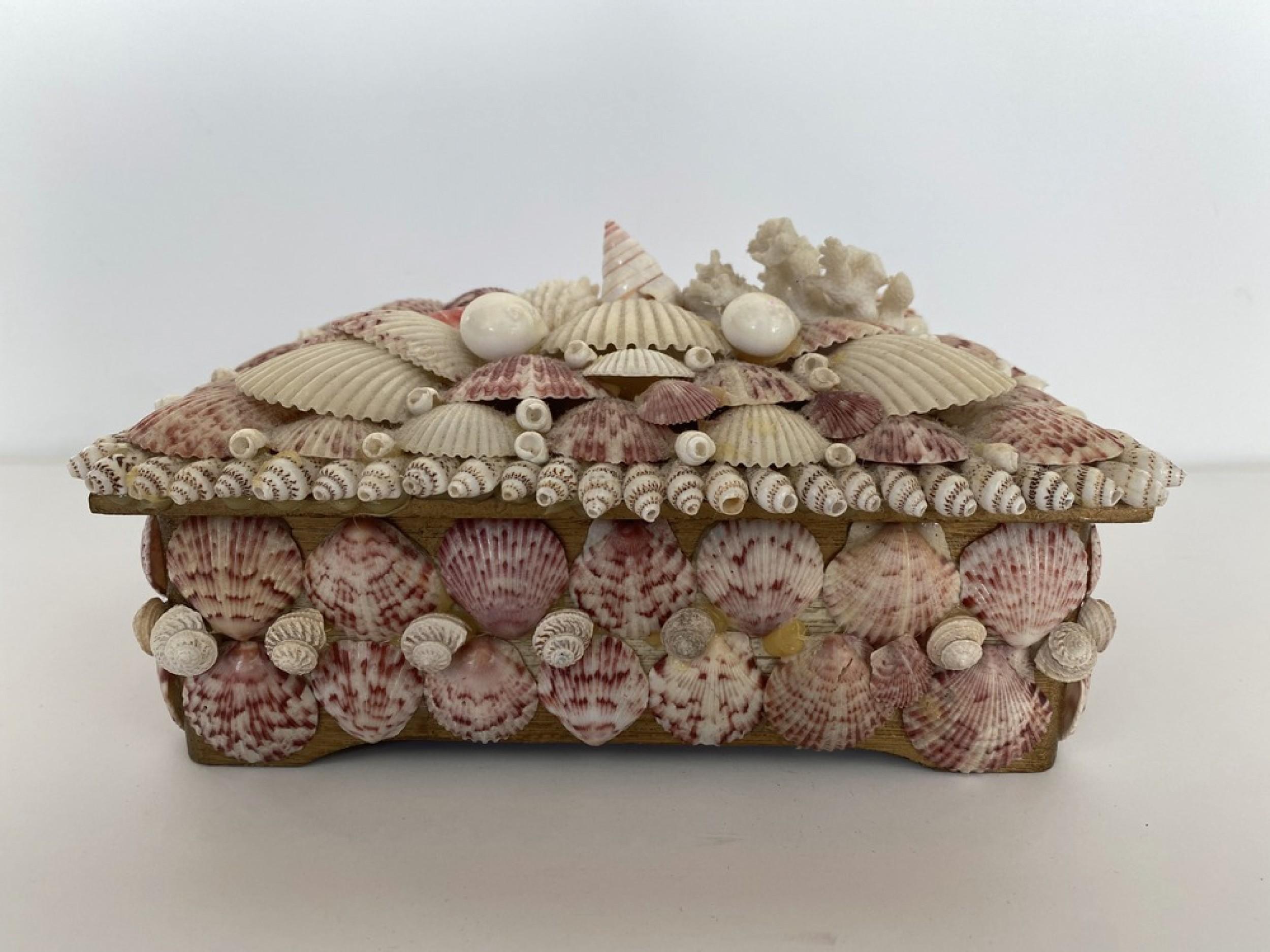 Contemporary American Modern music box / jewelry box with an exterior finished in beige and pink speckled seashells, which opens along a hinged edge to a red velvet interior, with a knob on the bottom that connects to an interior music box.