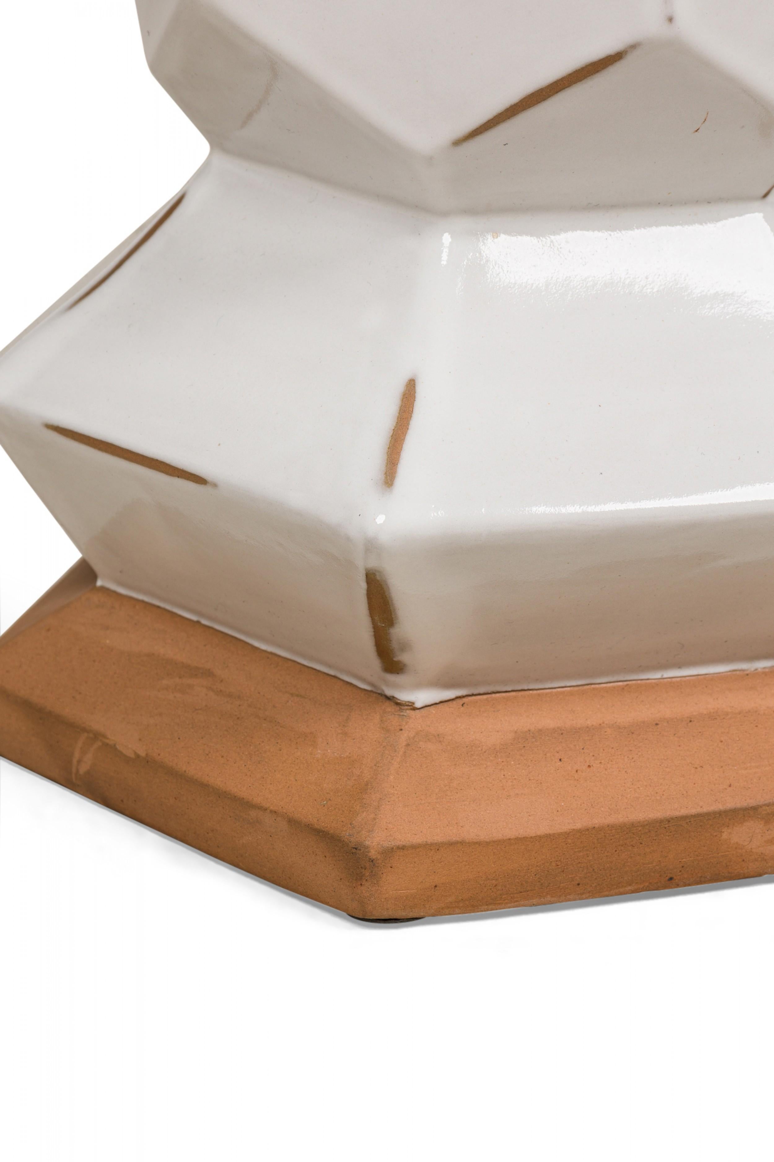Tavolino in ceramica americana contemporanea modellato in una forma tridimensionale a sei lati, cotto in uno smalto bianco opaco lucido con angoli e base alternati non smaltati come accenti decorativi.

Un angolo non smaltato riapplicato con lo