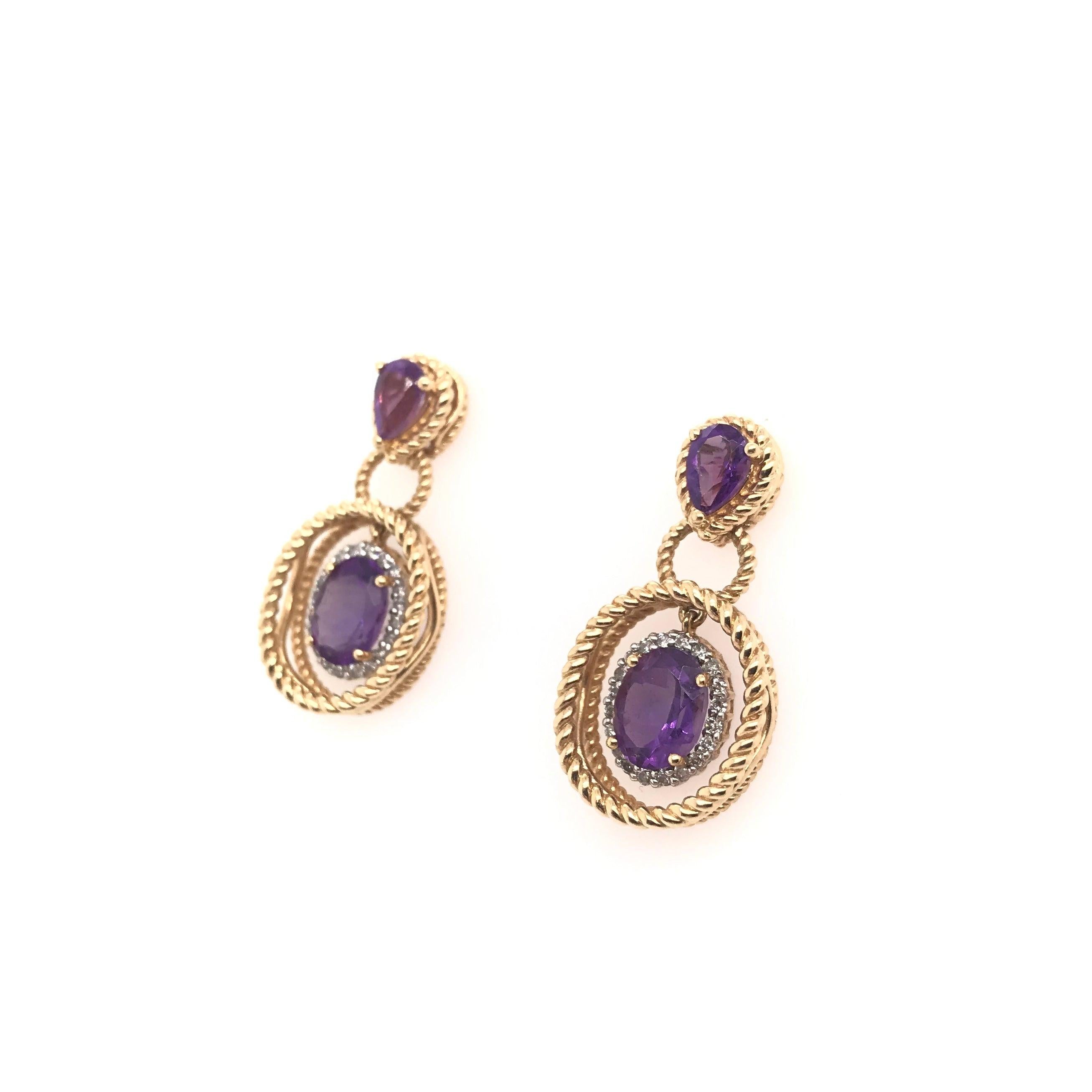 These amethyst and diamond drop style earrings are a contemporary piece. Each earring features one fancy pear cut amethyst along with an oval cut amethyst. Each oval cut is haloed beautifully by tiny sparkling diamonds. The 14k gold settings feature