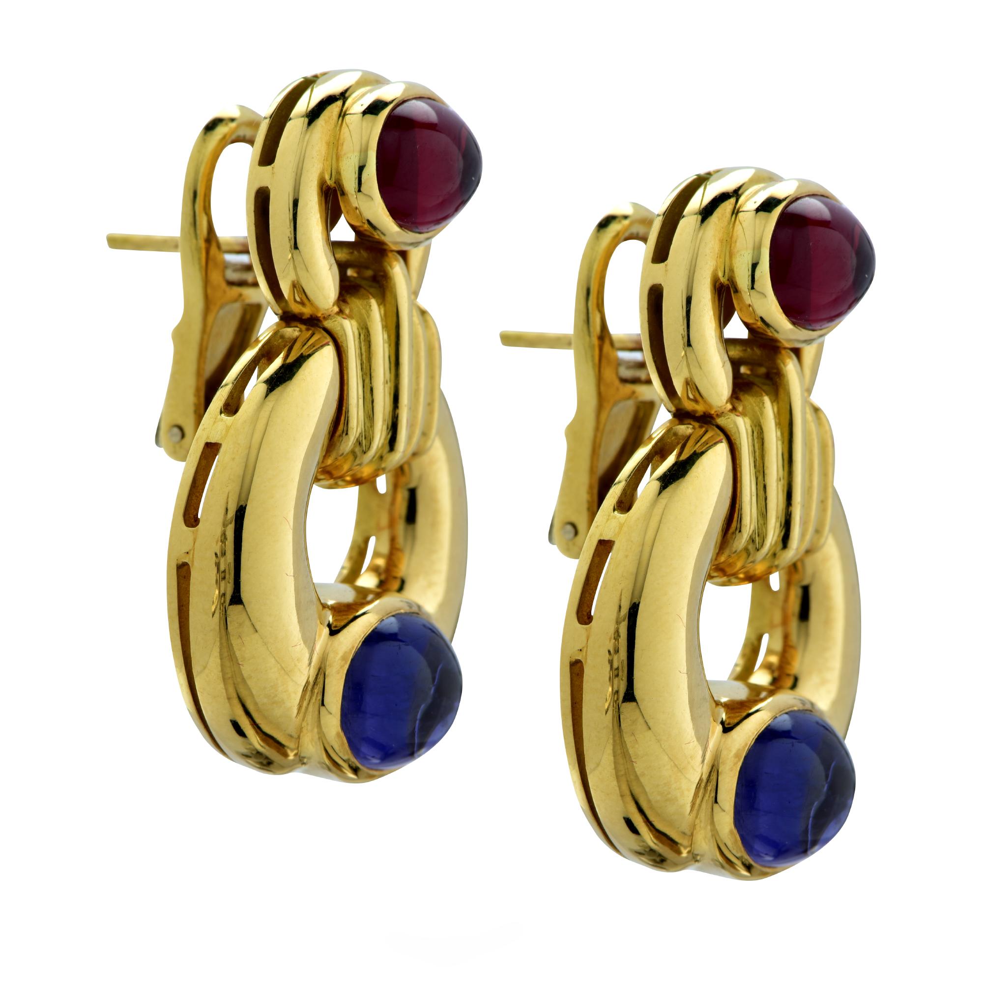 Gorgeous contemporary dangle earrings, crafted in 18 Karat yellow gold, featuring an oval cabochon garnet and an oval cabochon amethyst set in a circular design. These eye-catching earrings measure 1.35 inches in length and .92 inches at its widest