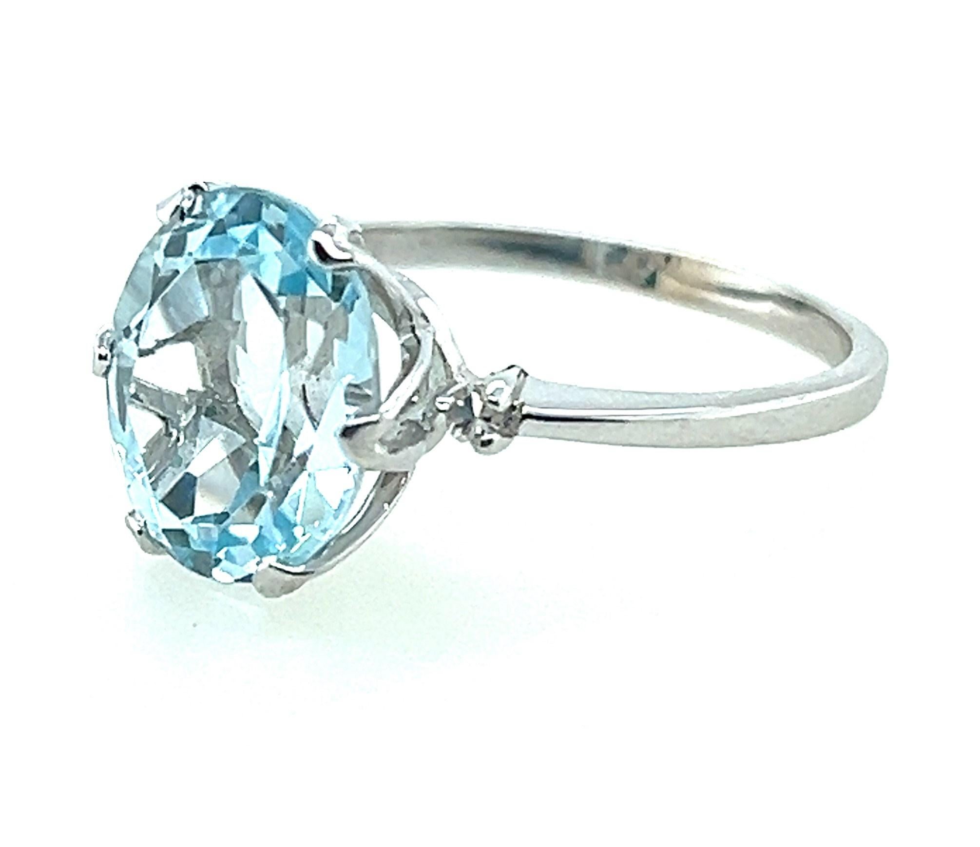 A bright and lively 4.25 carat faceted oval aquamarine shines with a soft sky blue glow between two tiny twinkling 0.05 carat single-cut accent diamonds.  The center oval aquamarine measures 12mm x 10mm x 6mm, set north-south, and is the center of