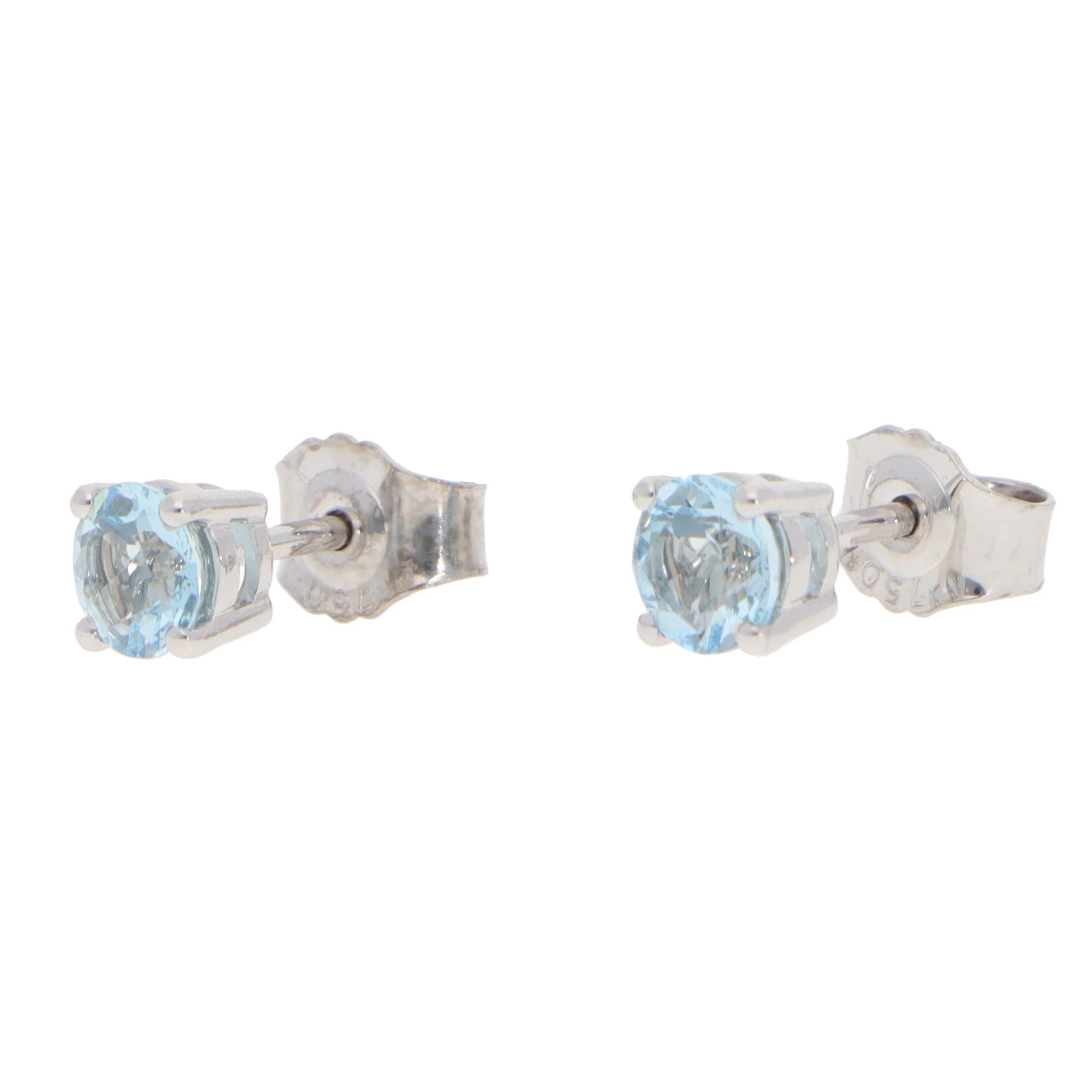 A beautiful pair of contemporary aquamarine stud earrings set in 18k white gold.

Each earring solely features a sparkly light blue round mixed-cut aquamarine, four claws set to centre. Each stud is set in an open-back setting and is secured to