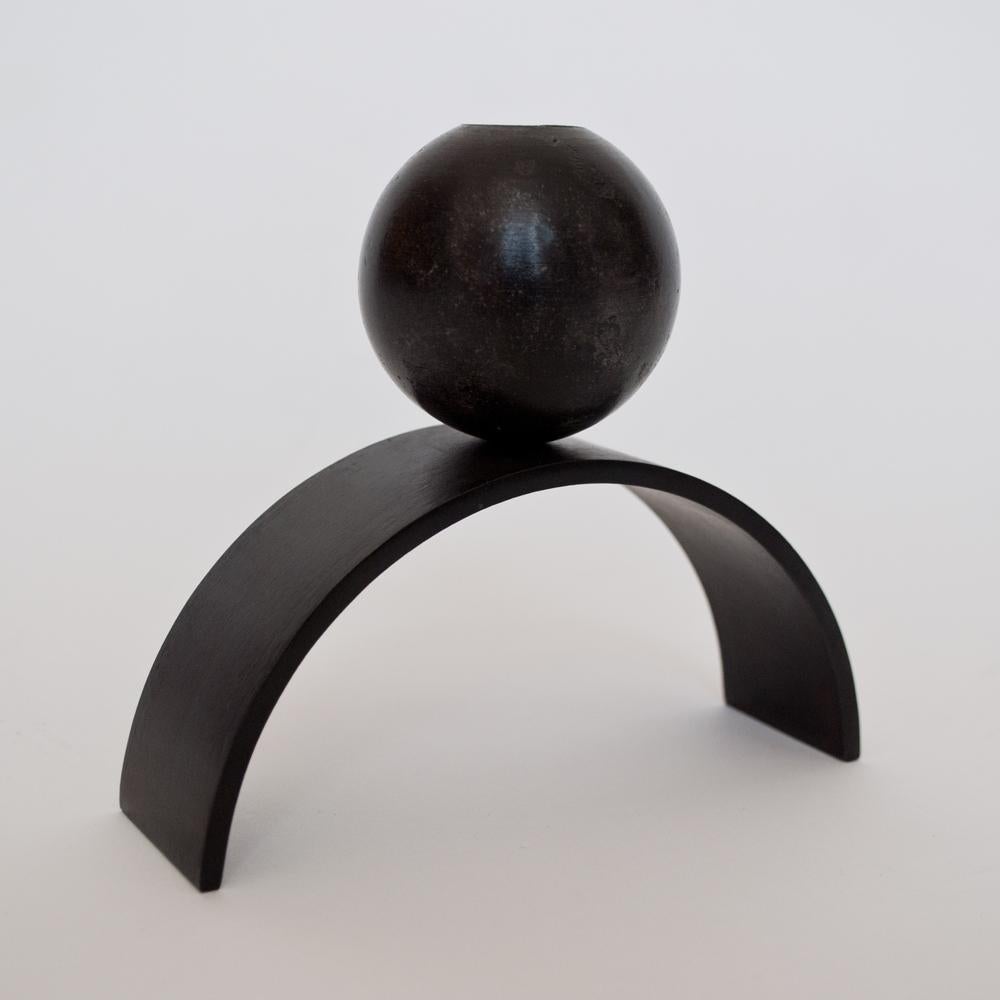 Louis Jobst' arch and ball extra large candle holder. The candle holder is machined from solid steel and patinated black. The candle holder shows off a contemporary form of an arch with a ball / sphere elegantly balancing on top. The design is