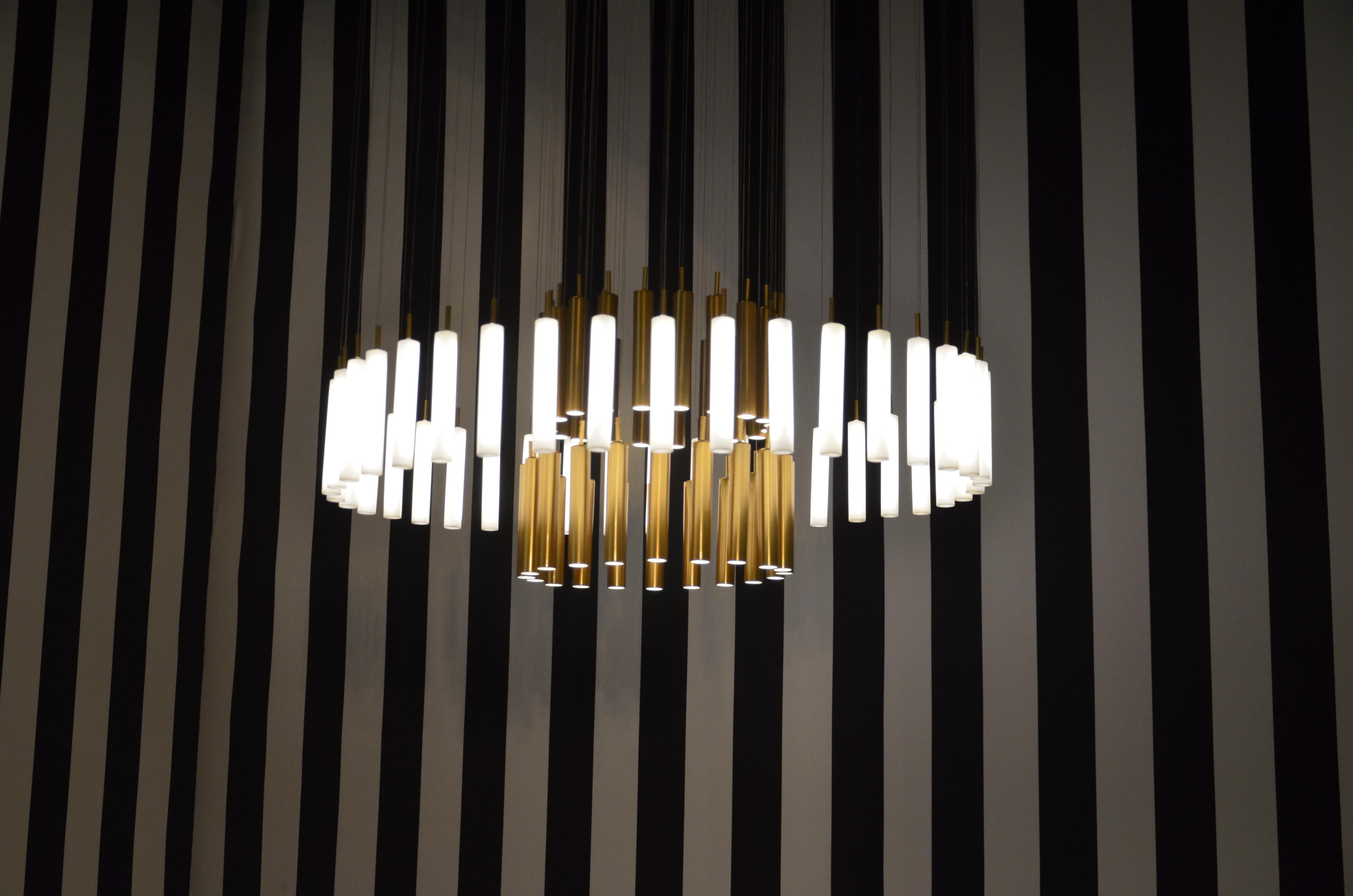 The Art-Déco rainy day bespoke chandelier is designed by Sylvie Maréchal and it is entirely manufactured in France. This chandelier is made of 80 Limoges Porcelain tubes of which 40 are fine golden tubes and 40 are white tubes. The tubes are