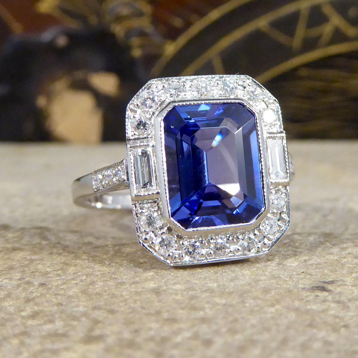 This statement cluster ring holds a 2.20ct Emerald Cut Tanzanite in a rub over collar setting with a Diamond surround. With a total Diamond weight of 0.50ct, these modern brilliant cut and baguette cut diamonds create an extra sparkle to this