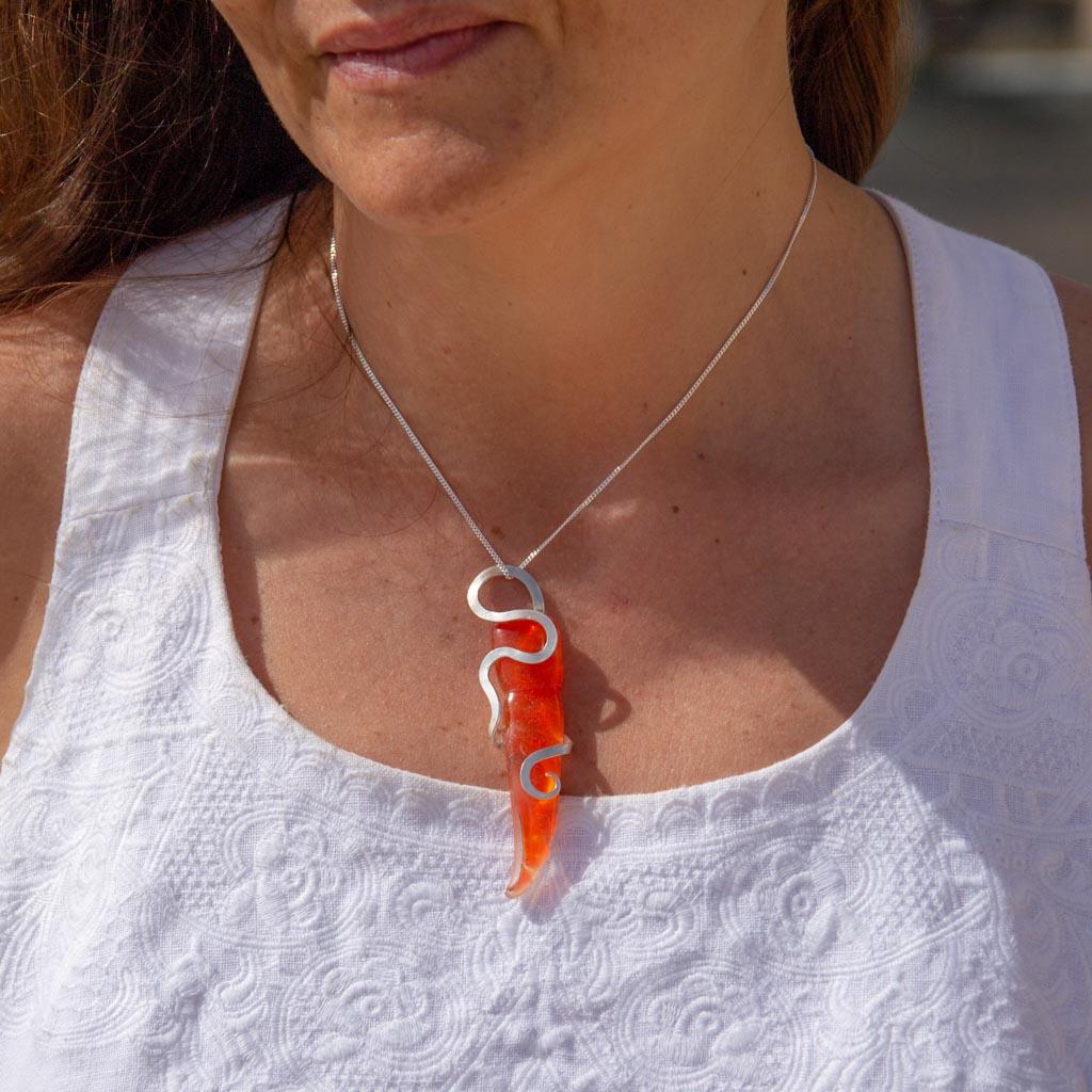 Award-winning Tara Lois was influenced by the Art Nouveau style when she designed this contemporary organic pendent. The abstract curves have been handcrafted from sustainable sterling / 925 silver fused to stunning orange Maltese glass.
This