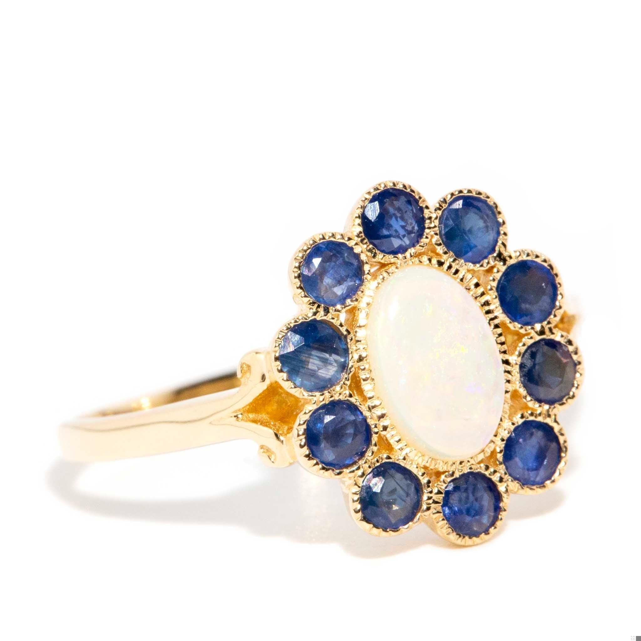 Der Carole-Ring mit seinem atemberaubenden Opal, umrahmt von reichhaltigen blauen Saphiren, ist eine Anspielung auf eine glamouröse Vergangenheit. Beeinflusst von einer Ära, in der Technicolour in all seiner lebendigen Pracht herrschte, ist sie ein