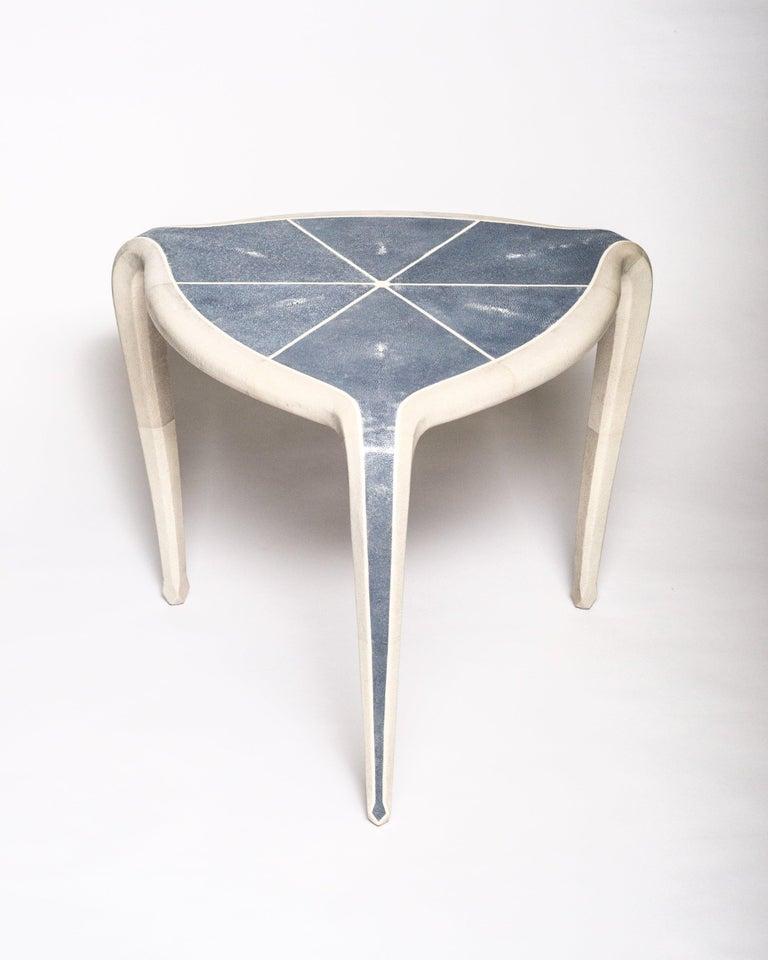 A sophisticated blend of texture, tone, and form, this tripod side table is a masterclass in refined design. Crafted with a walnut veneer wood frame, the piece is fully wrapped in blue and crème shagreen, offering a soft, tactile contrast that