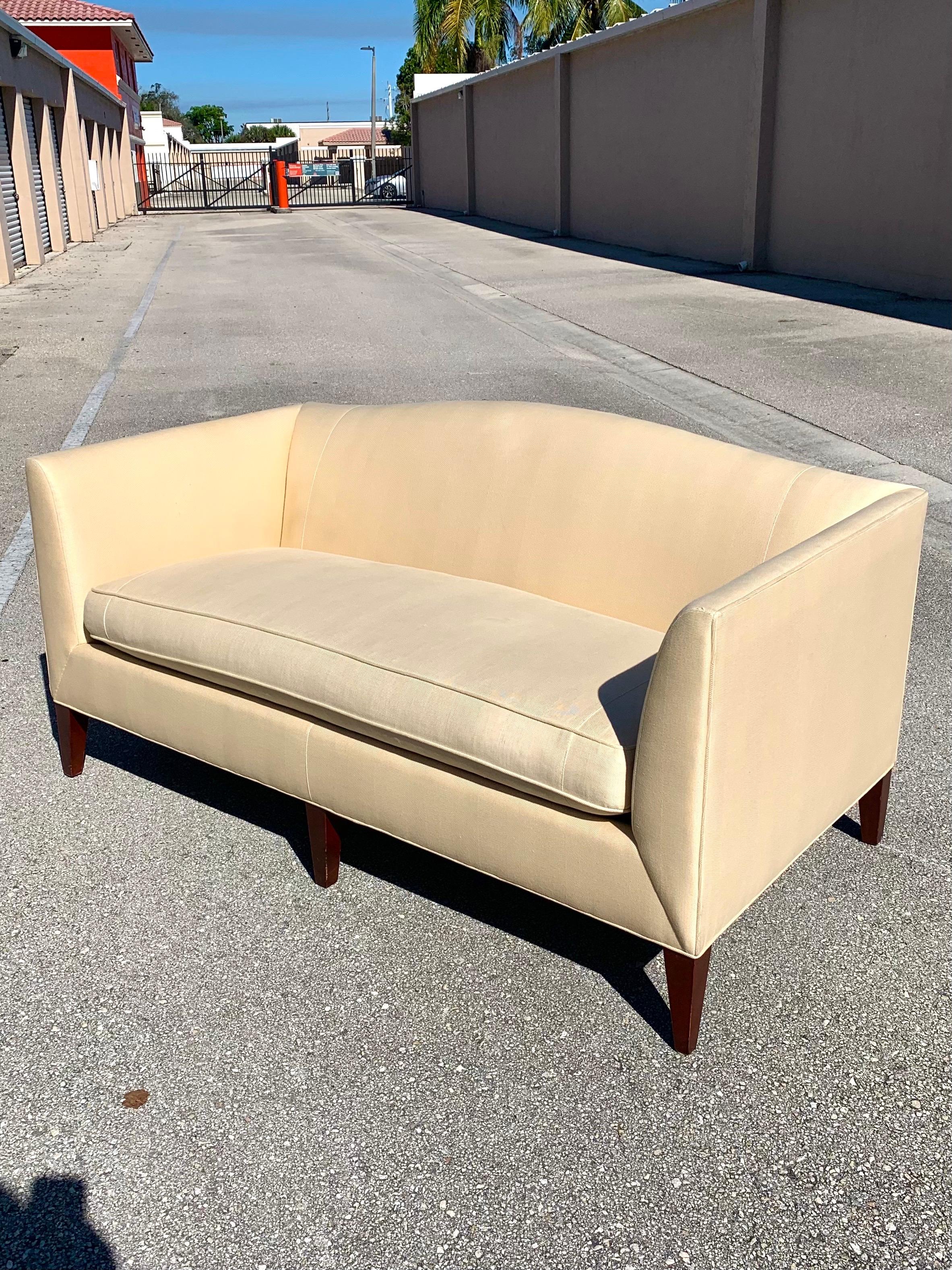 Baker Archetype Camelback sofa in a high quality eggshell upholstery. Cushions made of both foam and down. Knife arm design and squared tapered legs. From a Palm Beach estate.