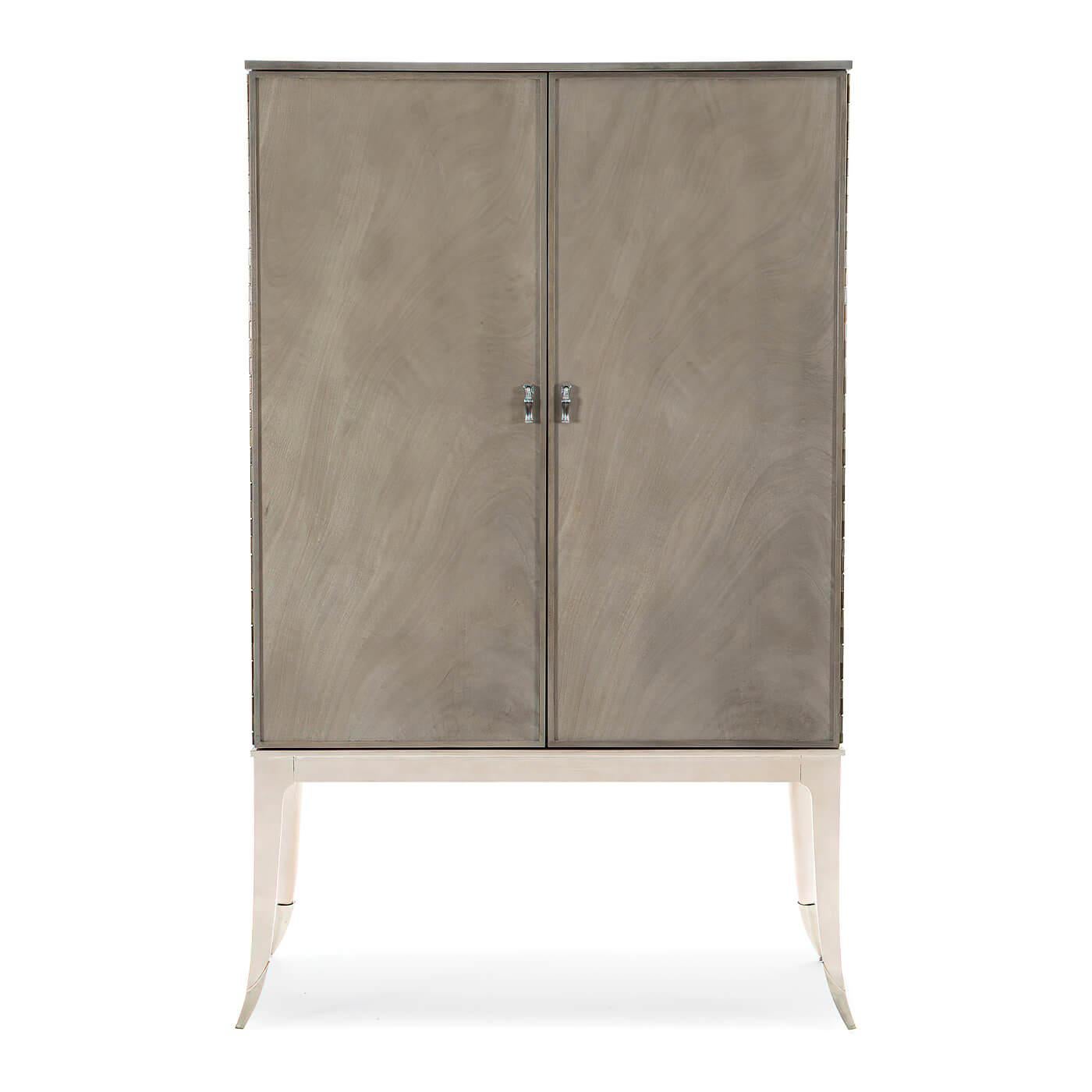A contemporary silver two-door bar cabinet with splayed legs in silver leaf with metal ferrules in lightly brushed chrome. The case has been given our silver fox finish and has a silver-painted interior. The two doors with piano hinges.

Inside it