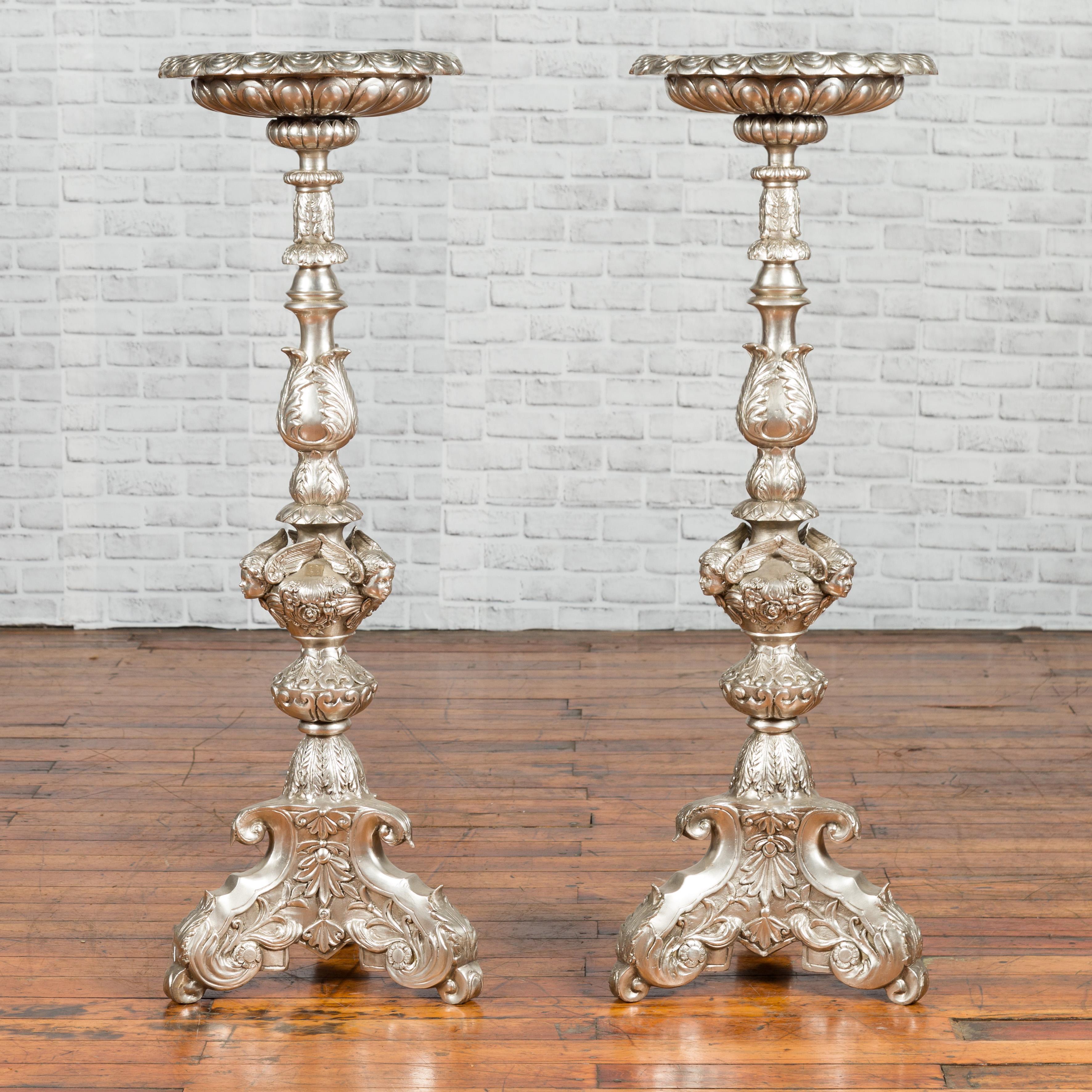 A Baroque style limited edition silver plated bronze candlestick with cherubs and tripod base. We have two available, priced and sold individually. This limited edition Baroque style silver-plated bronze candlestick captivates with its grand