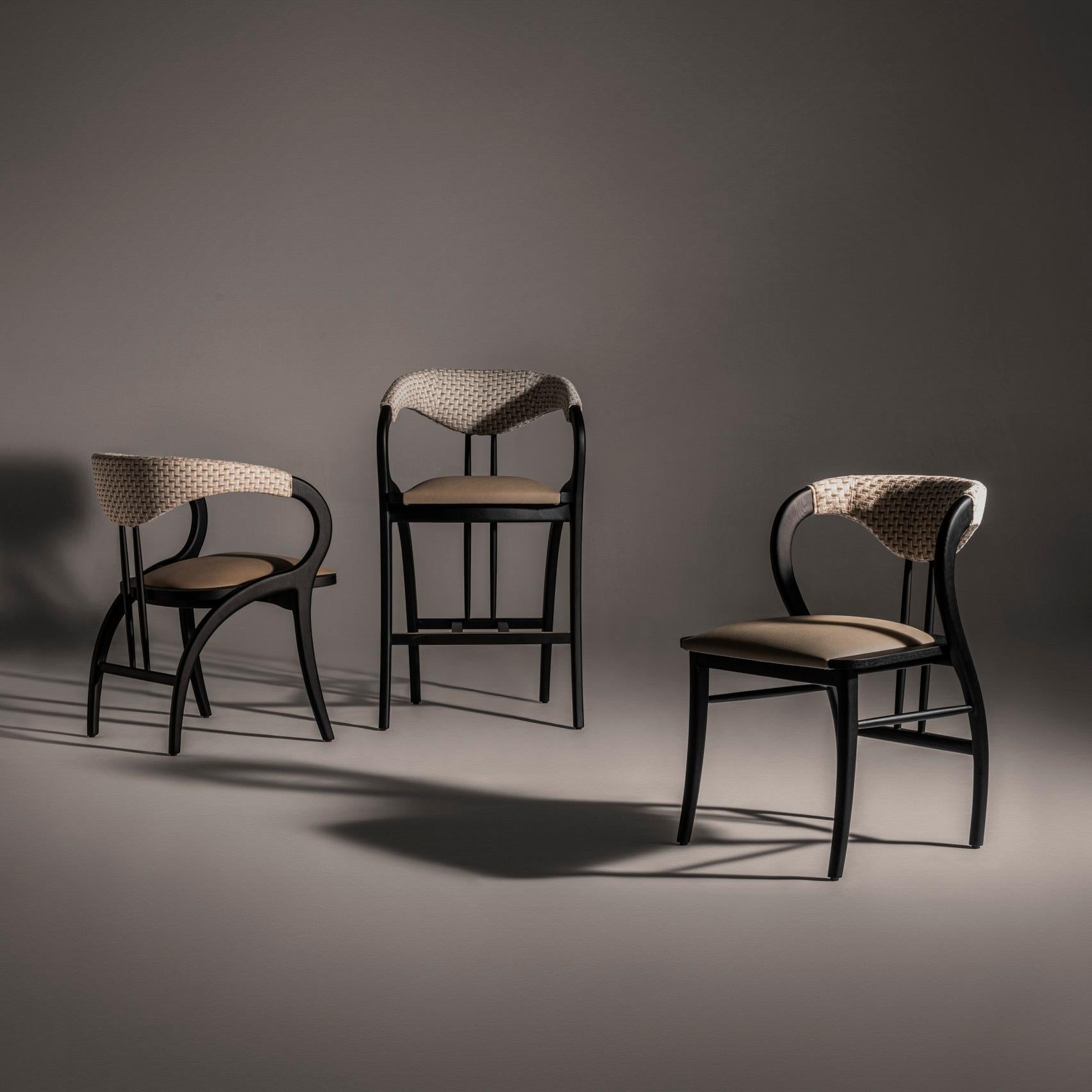 This barstool embodies a classic elegance while prioritizing comfort.  It's expertly constructed using a sophisticated combination of materials: luxurious fabric upholstery and the natural beauty of durable ash wood.  The design likely balances form