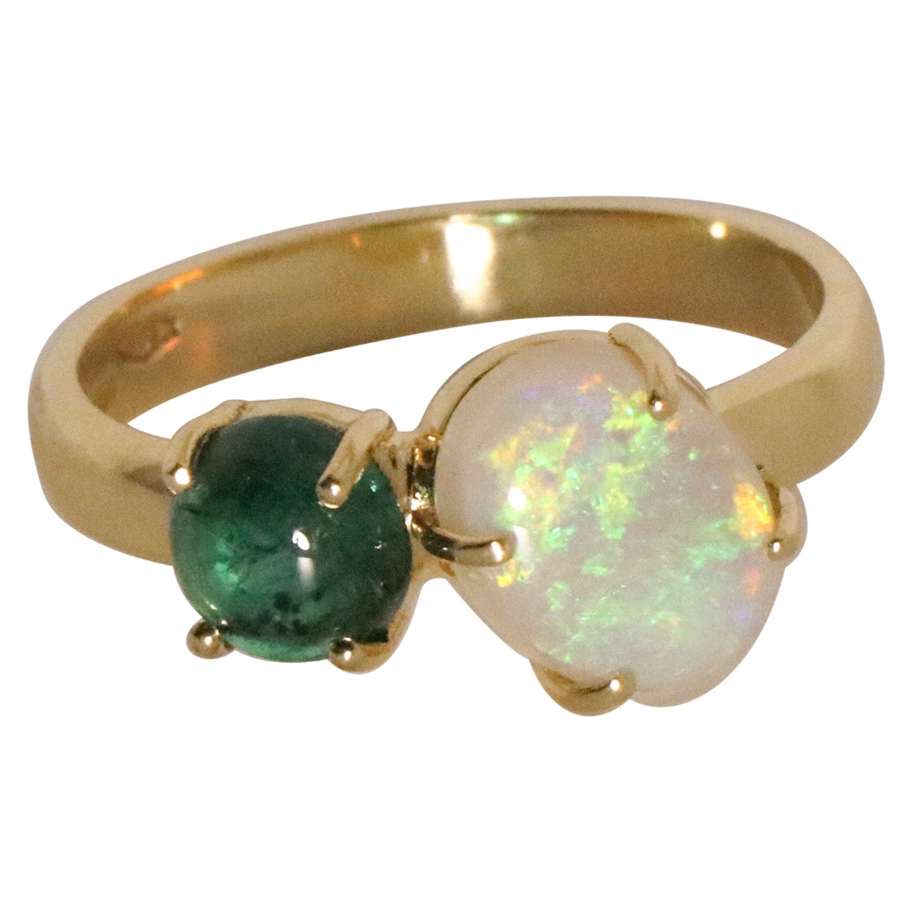 Der Ring Ines besteht aus 18 Karat Gelbgold und enthält einen natürlichen Smaragd mit rundem Cabochon-Schliff von ca. 0,8 Karat, Durchmesser 5,9, Tiefe 3,05 mm und einen hochwertigen australischen Opal mit ovalem Cabochon-Schliff von ca. 1,4 Karat,