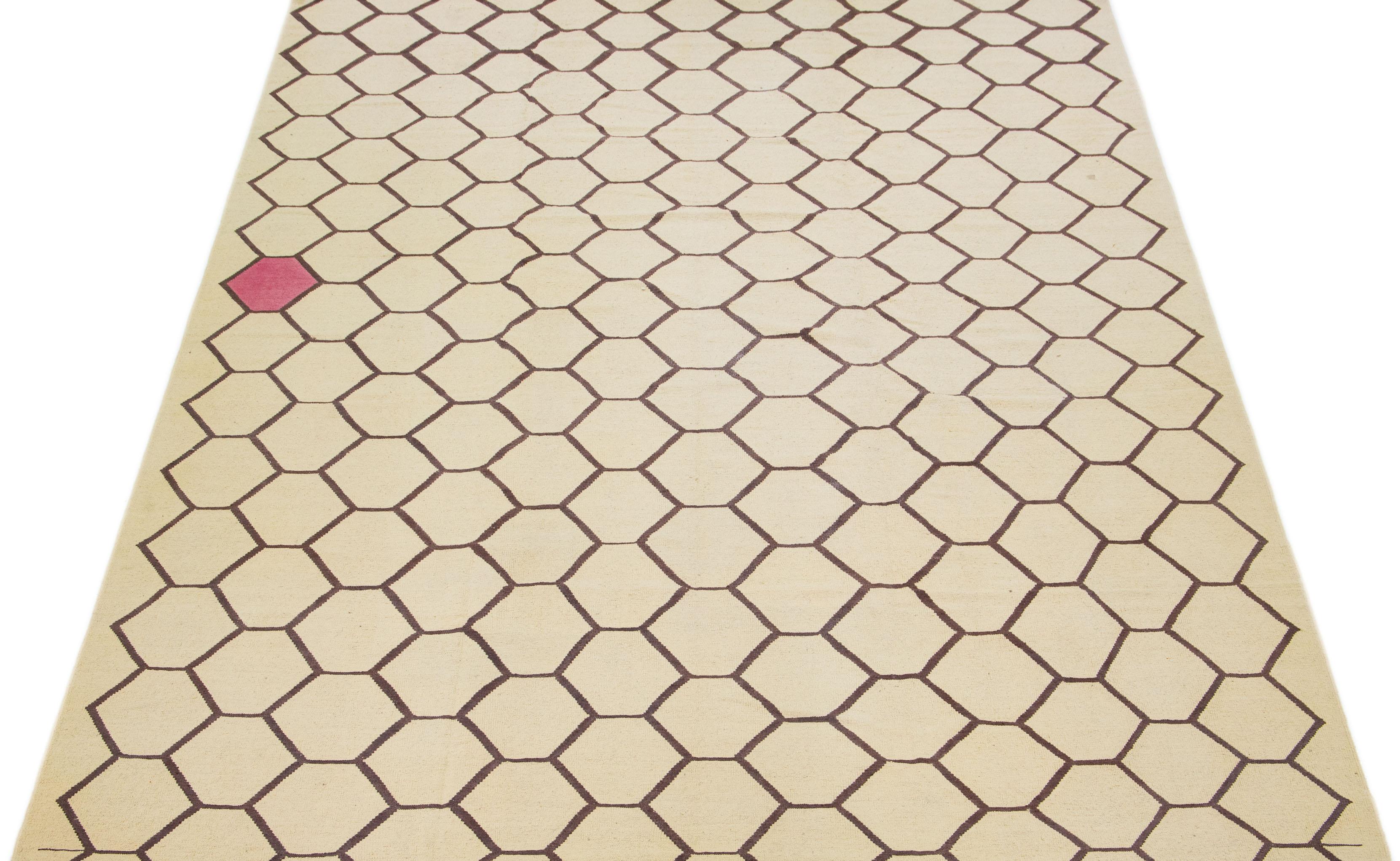 Dieser moderne Kilim-Teppich wurde fachmännisch von Hand geknüpft und besticht durch ein beigefarbenes Feldmuster, das durch subtile Braun- und Rosatöne innerhalb des geometrischen Musters ergänzt wird.

Dieser Teppich misst 10'4