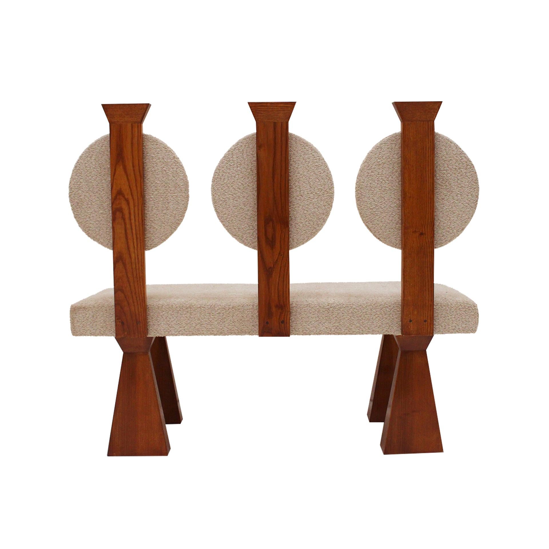 Architettonicamente raffinata e radicata nella tradizione artigianale, questa panca contemporanea è meticolosamente realizzata in legno massiccio di quercia e rivestita in pregiato bouclé di lana, offrendo un sofisticato gioco di texture e