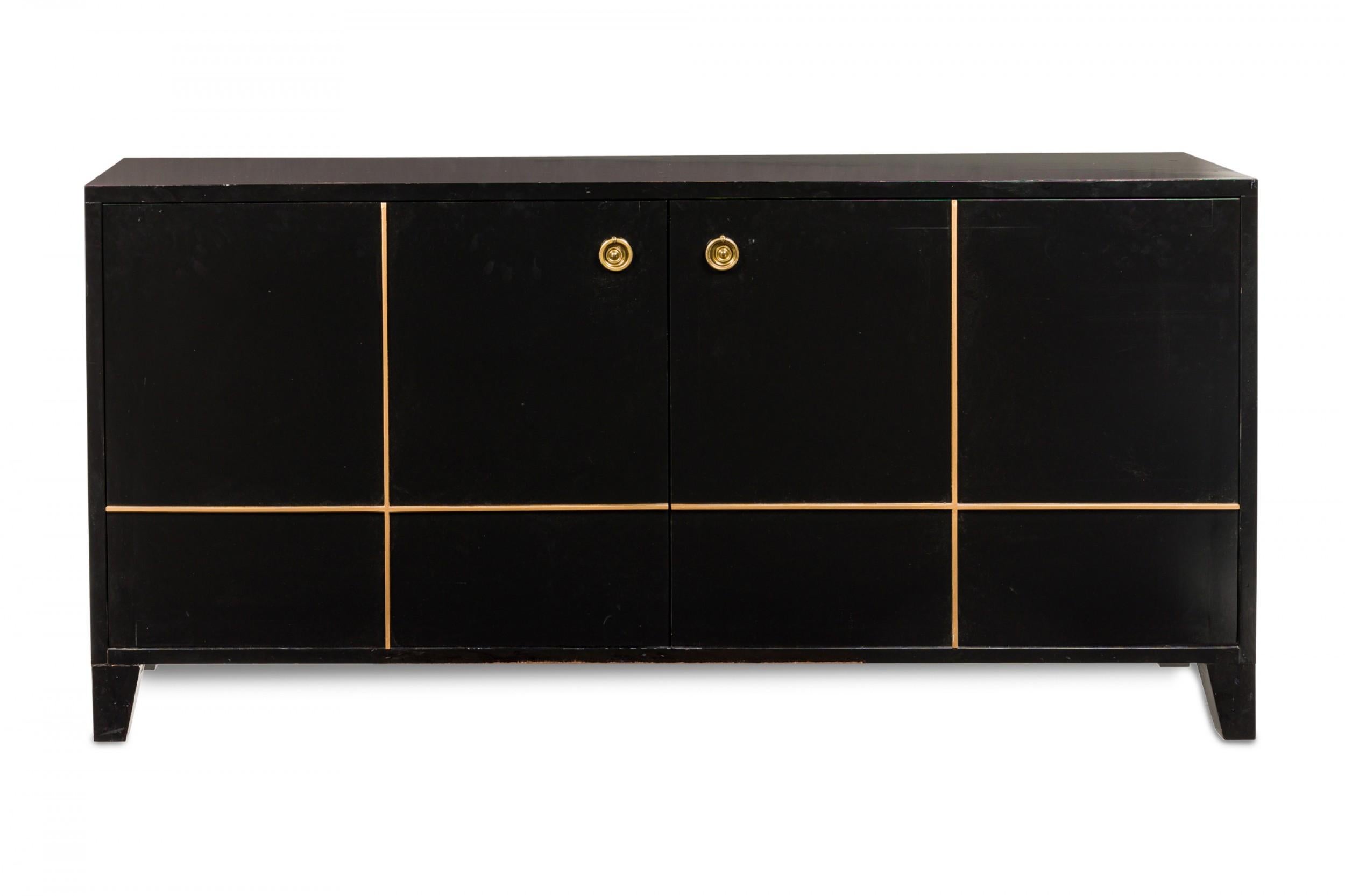 Contemporary American rectangular console cabinet / sideboard with a black painted finish and gilt geometric trim applied to the front, two cabinet doors with circular gilt metal ring handles opening to reveal two interior compartments with four