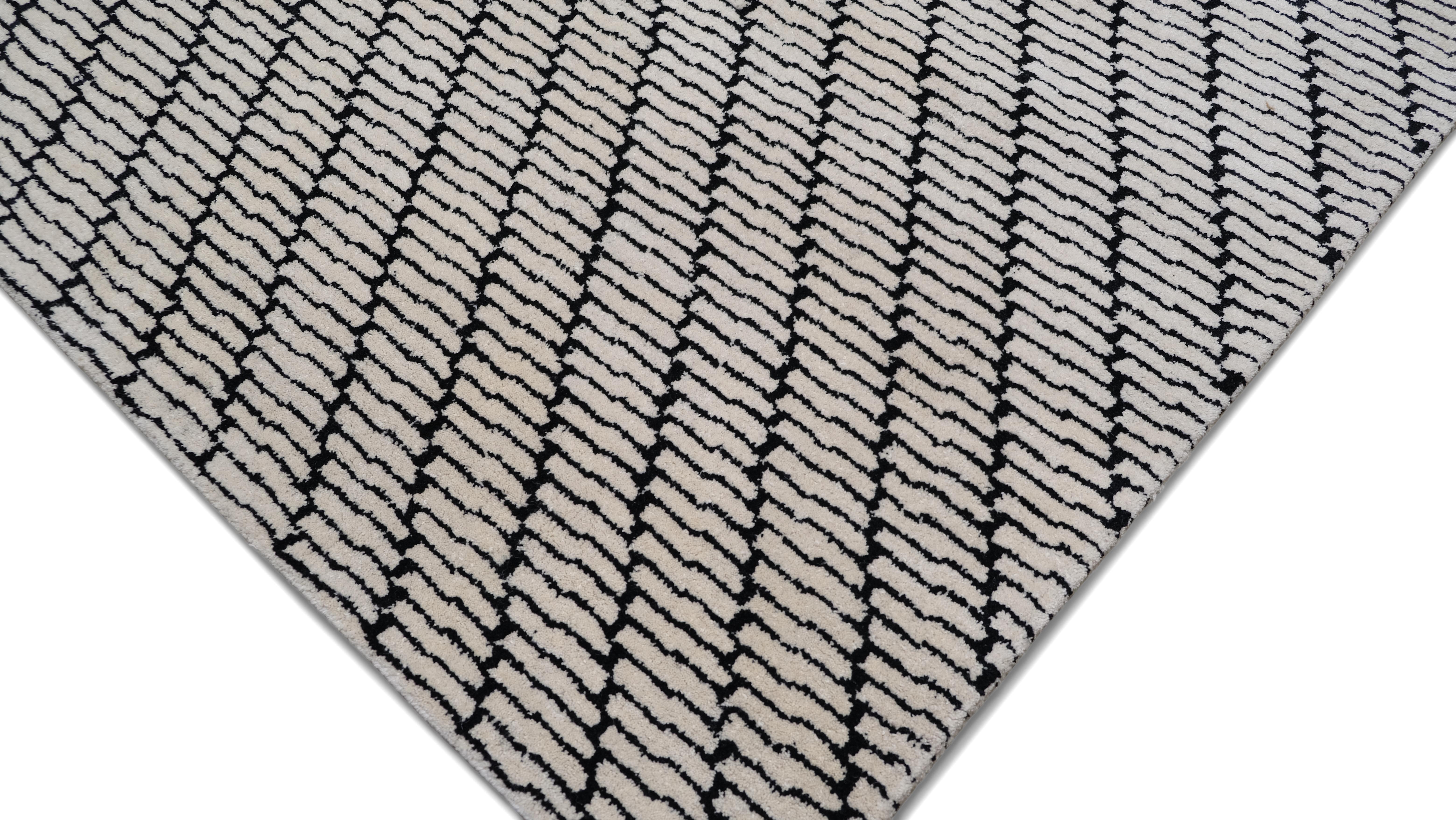 Dieser Wollteppich aus Indien zeichnet sich durch ein faszinierendes diagonales geometrisches Muster aus, das ein auffallendes Gefühl von Bewegung und Tiefe vermittelt. Das verschlungene Design aus gestapelten linearen Elementen bietet eine