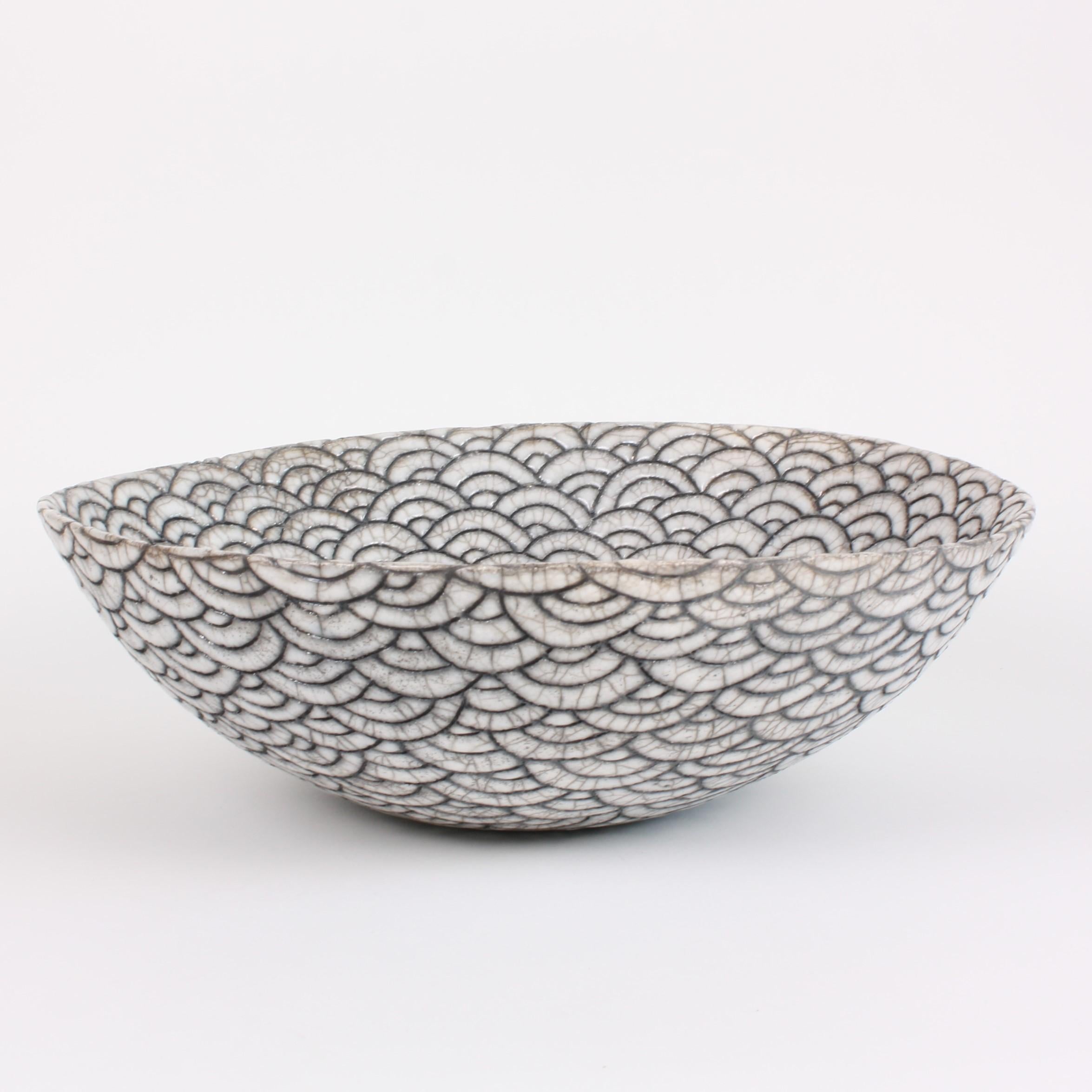 Decorative contemporary black and white ceramic raku coupe by artist Camille Campignion. Inspired by the Japanese seigaiha (or wave motif), the artist has individually engraved, freehand, hundreds of waves on the hand-coiled piece. The distinctive