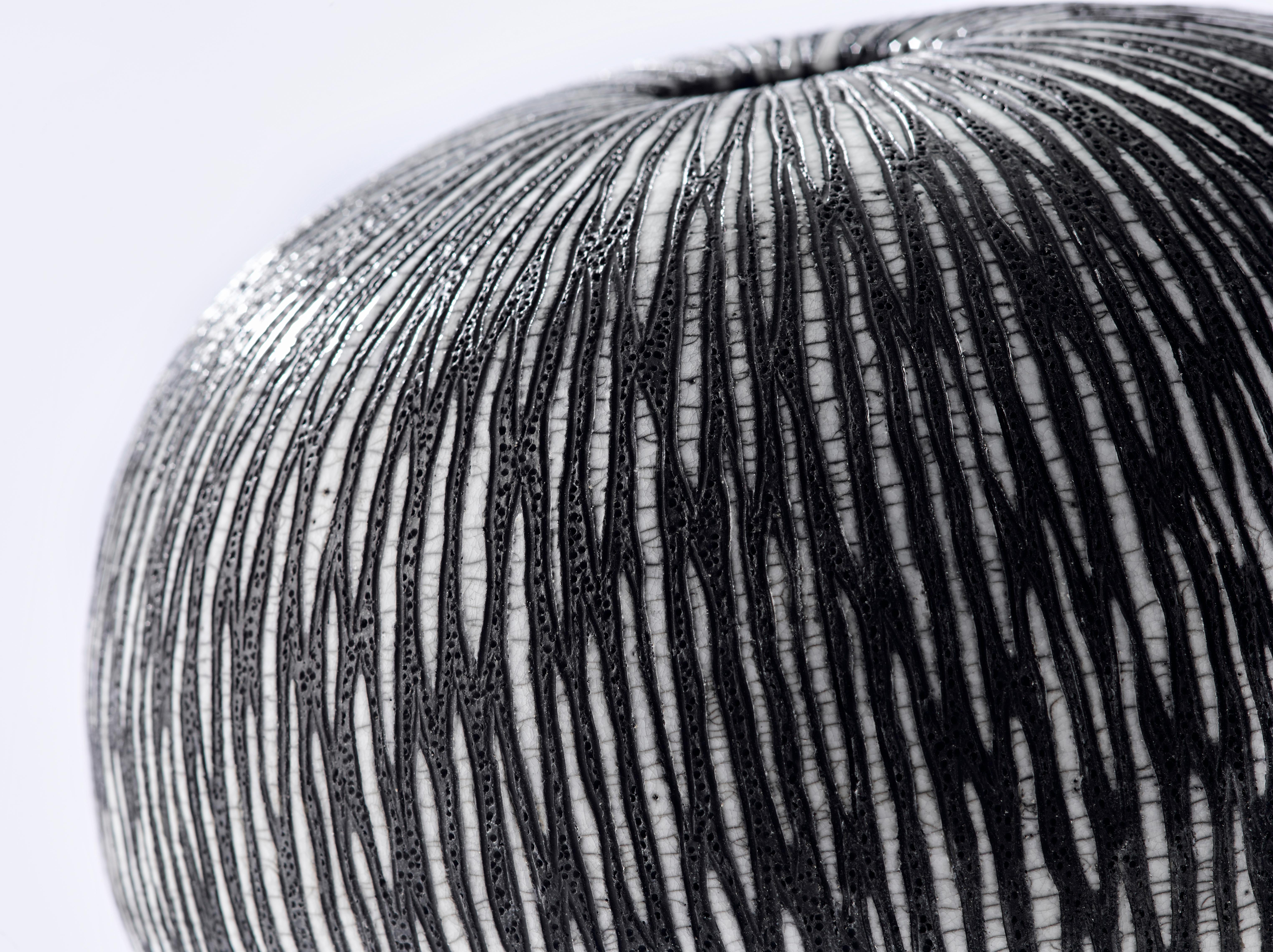 Contemporary black and white ceramic globe vase, Medium Boule Strate. The striped motif is graphic and modern, yet remains natural and organic, suggestive of an exotic fruit or a sea-urchin shell. The distinctive crackles of the raku technique make