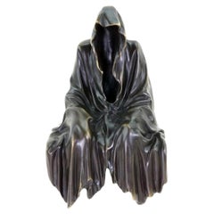 Escultura contemporánea de un fantasma sentado en una estantería, en bronce negro