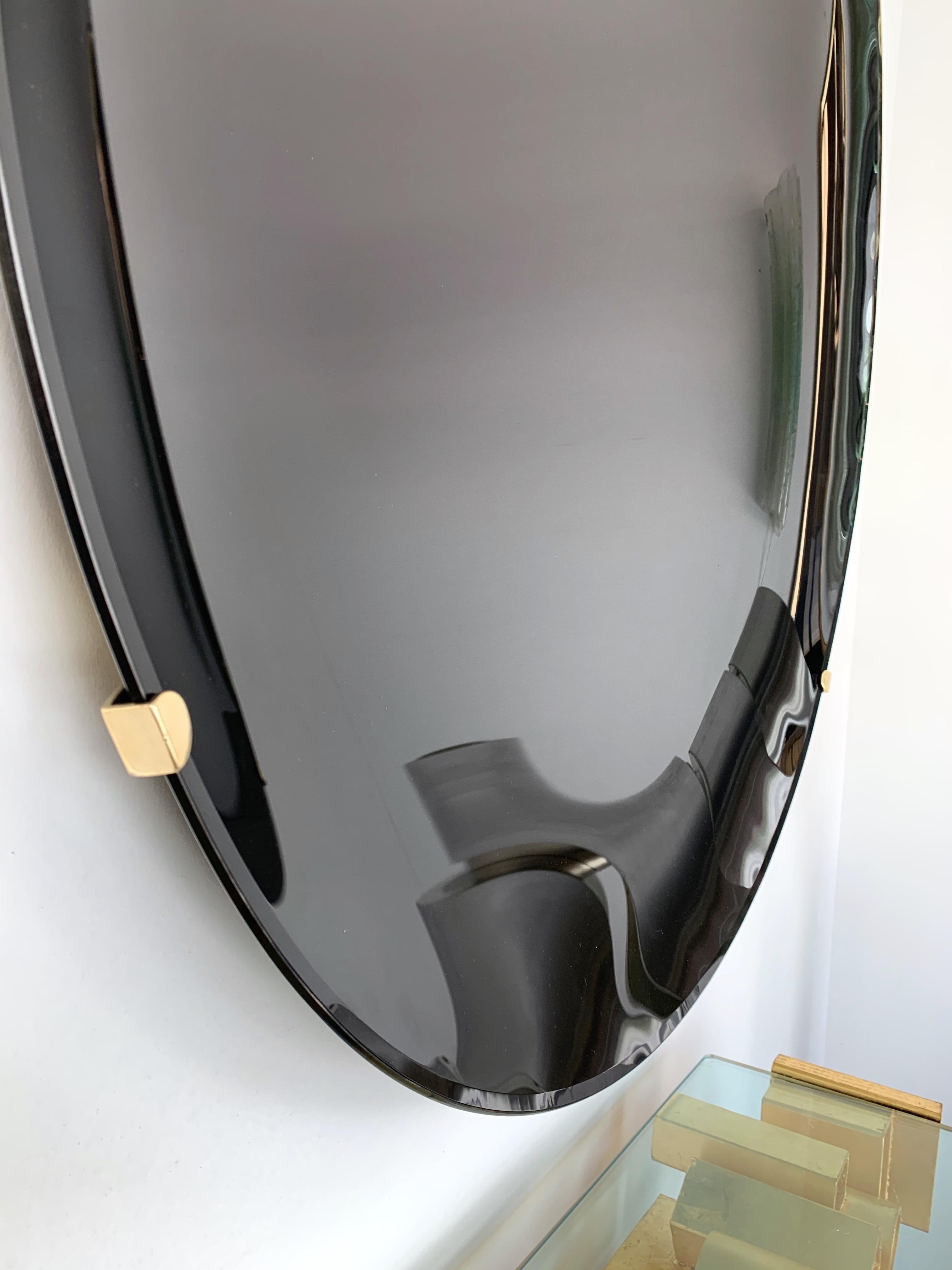 Contemporary curve concave sculpture black wall mirror, brass structure. Artisanal handmade work made by a small italian workshop using the old style mercurization technic. 