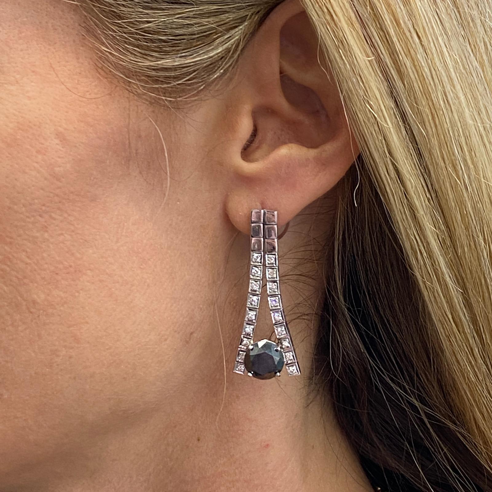 Fabulous black diamond drop earrings fashioned in 14 karat white gold. The earrings feature 2 round brilliant black diamonds weighing 8.42 carat total weight. The earrings also feature 36 round brilliant white diamonds weighing 1.25 carat total