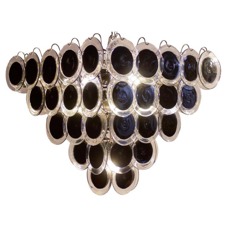 Black Murano glass disc chandelier one round shape and one pyramid shape. 
Each chandelier is made of 50 black discs of precious Murano glass and arranged on five levels.

 Nine light bulbs E 27. wired for US standards.