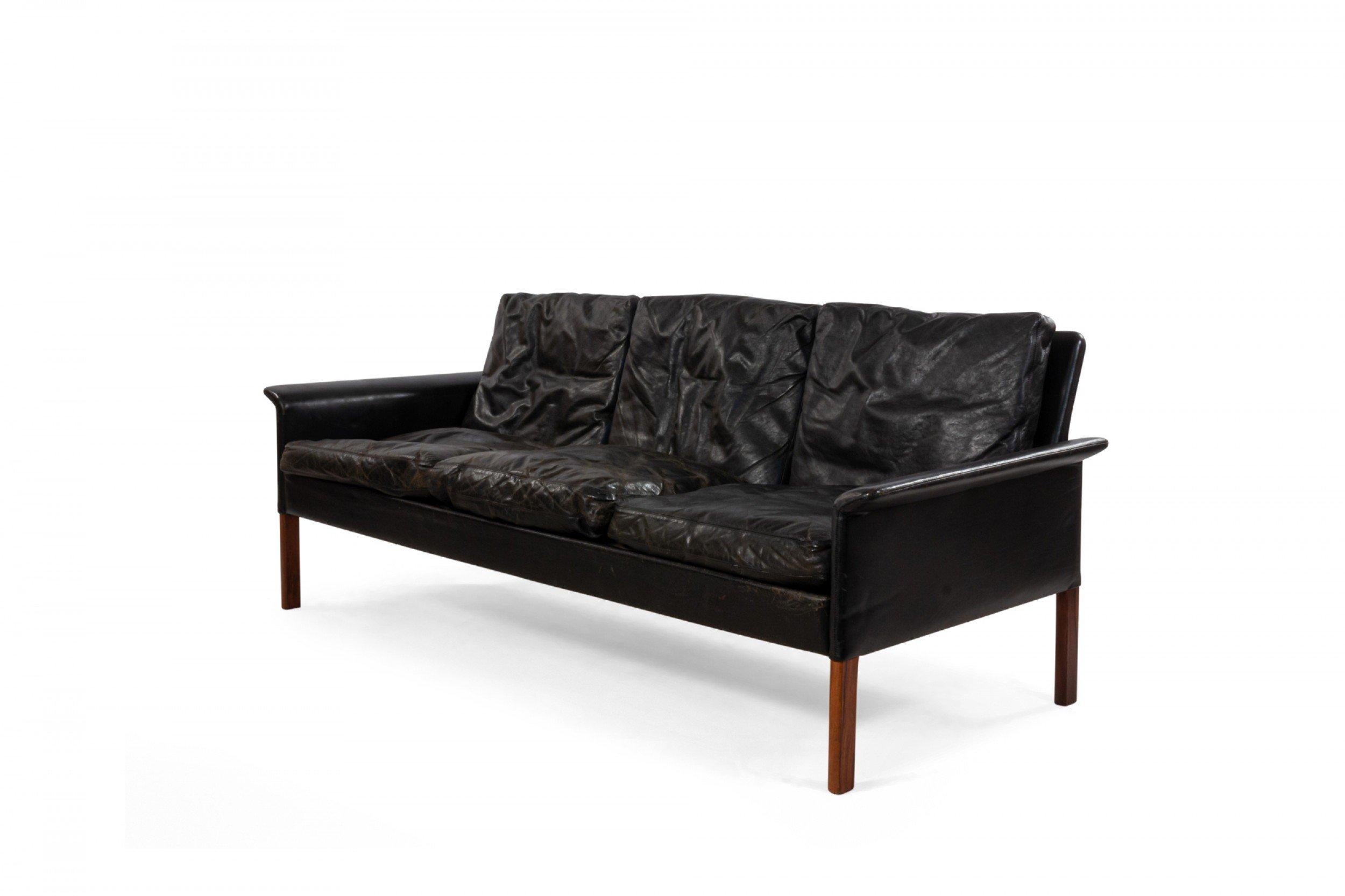 Midcentury Danish style black leather three-seat sofa with removable back and seat cushions and straight teak legs.