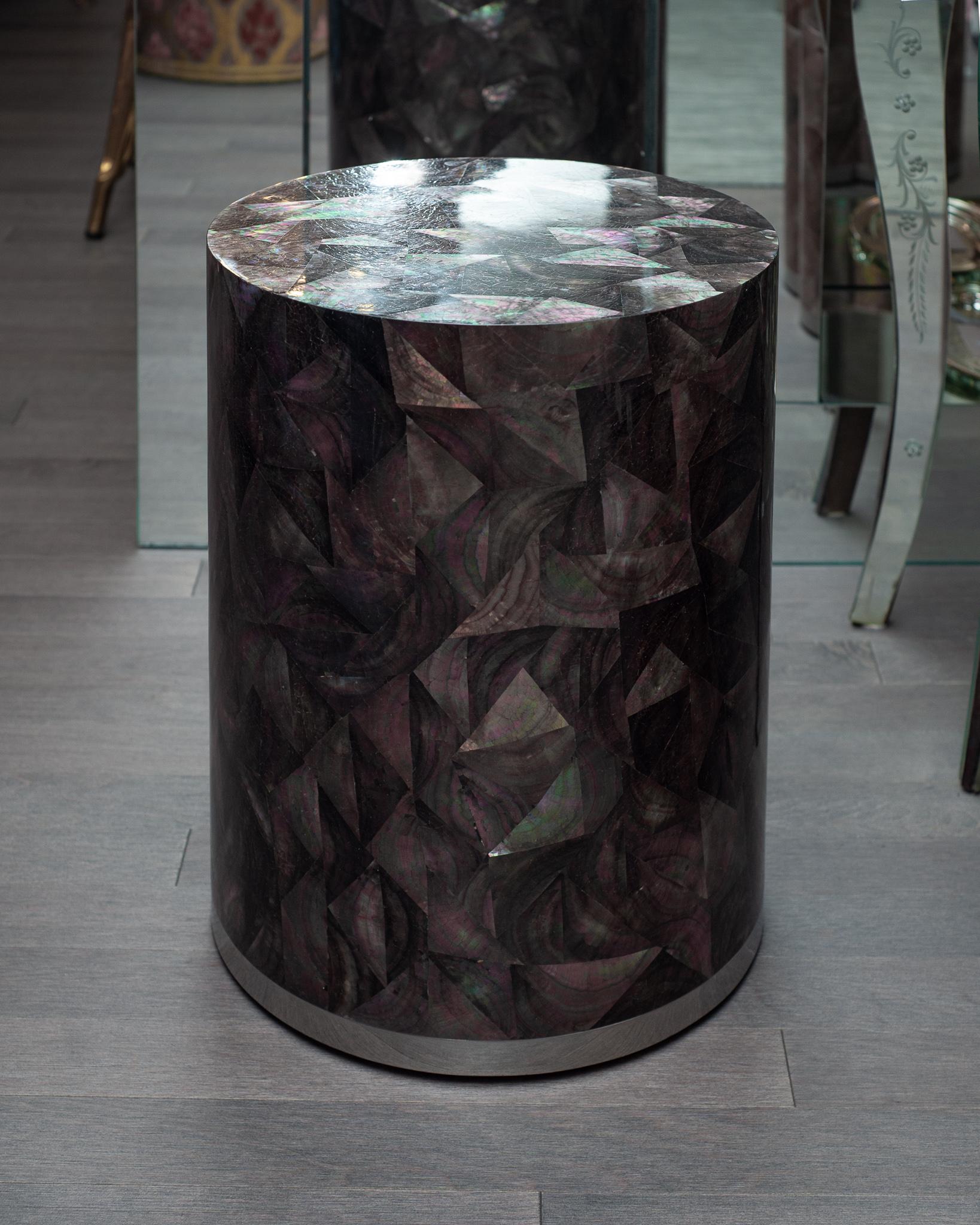 A stunning contemporary drum table finished in black mother of pearl with polished stainless steel trim at the base. Masterfully created and flawlessly executed, this shell drum table boasts a rainbow of tones dispersed amongst the black mother of