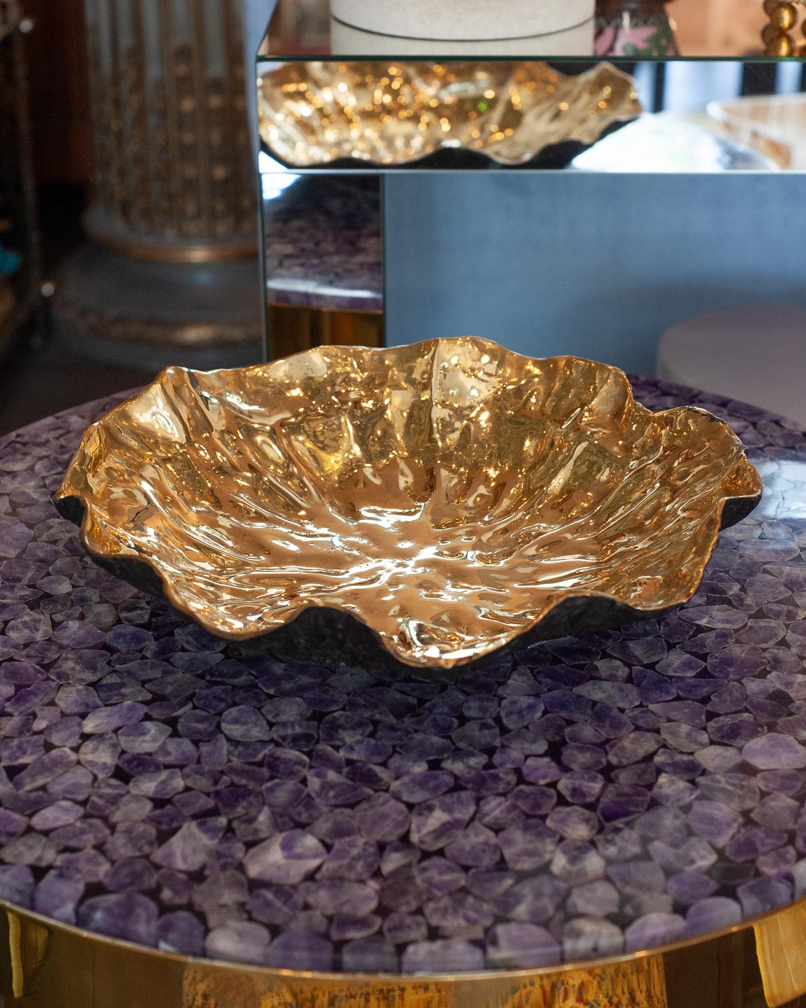 Evocando la serena geometria di una ninfea galleggiante, questo vassoio scultoreo in ottone fuso contrappone un interno dorato e lucido a un esterno robusto e annerito. La superficie liscia e radiante all'interno cattura e ingrandisce la luce,