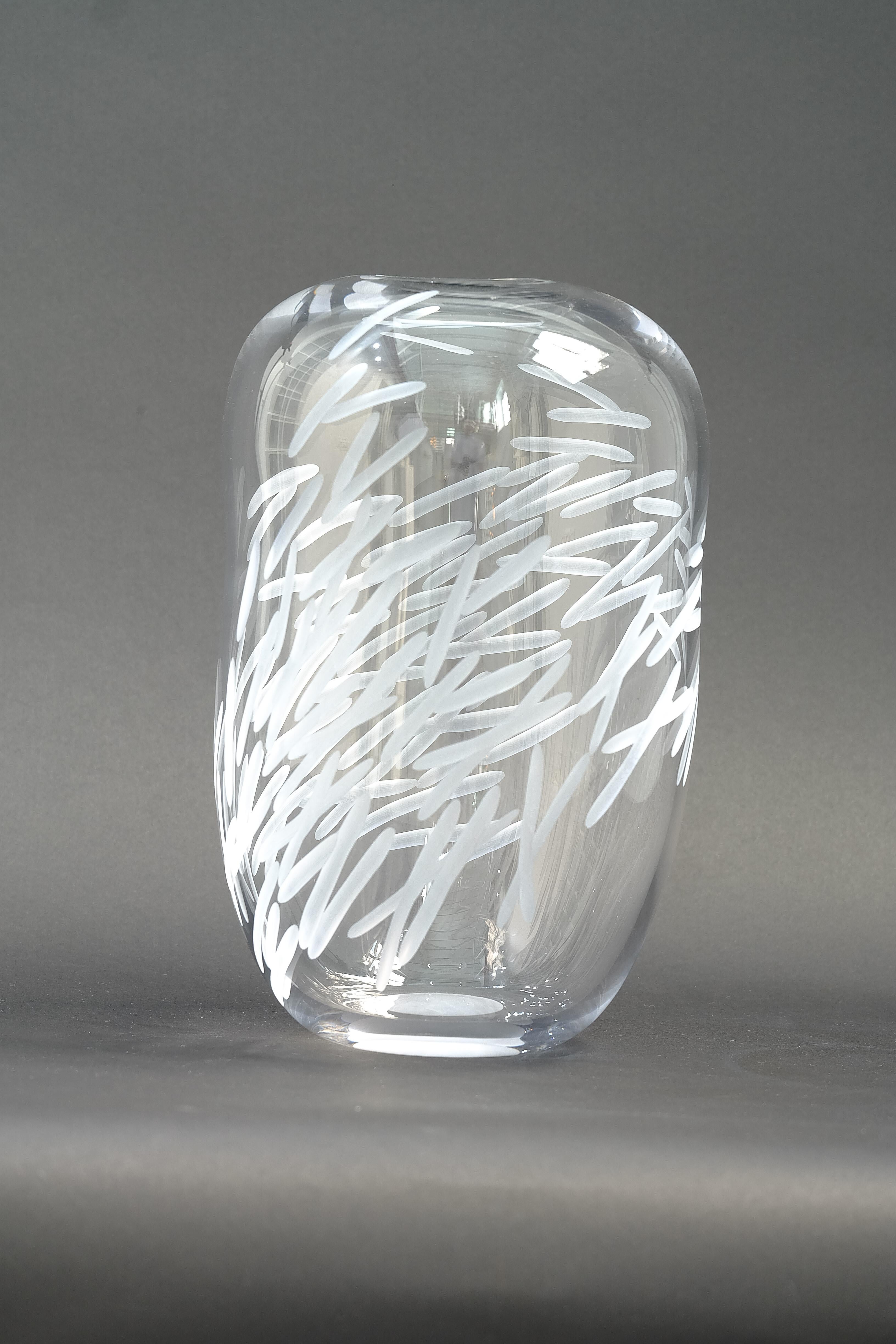 A clear glass vase blown and engraved by design duo Vezzini & Chen.

Vezzini & Chen’s work is defined by the artful marriage of hand carved ceramics and blown glass. The collections tread a fine line between functional and conceptual, with the