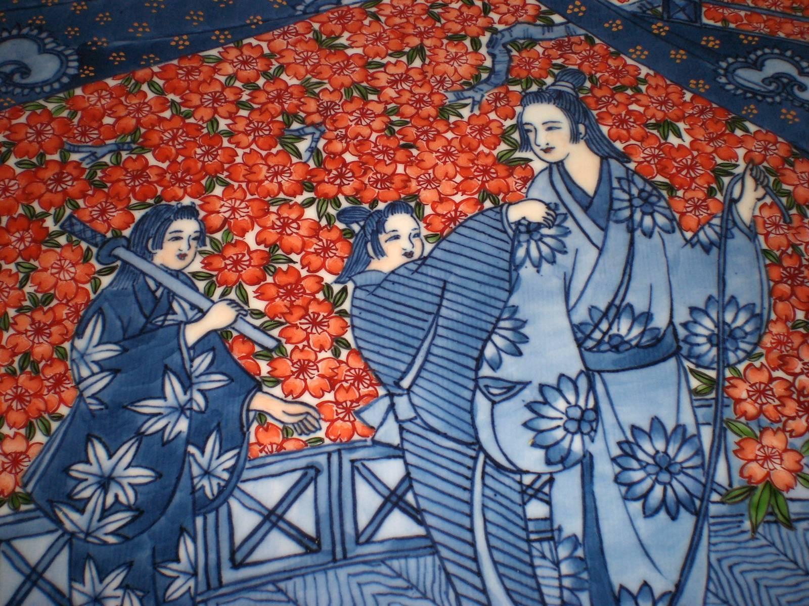 Cet exquis chargeur en porcelaine décorative japonaise contemporaine rouge et bleue est un chef-d'œuvre signé par un maître porcelainier de la région d'Imari-Aita, dans le sud de l'île de Kyushu, au Japon (1931-2009). Le chargeur peint à la main