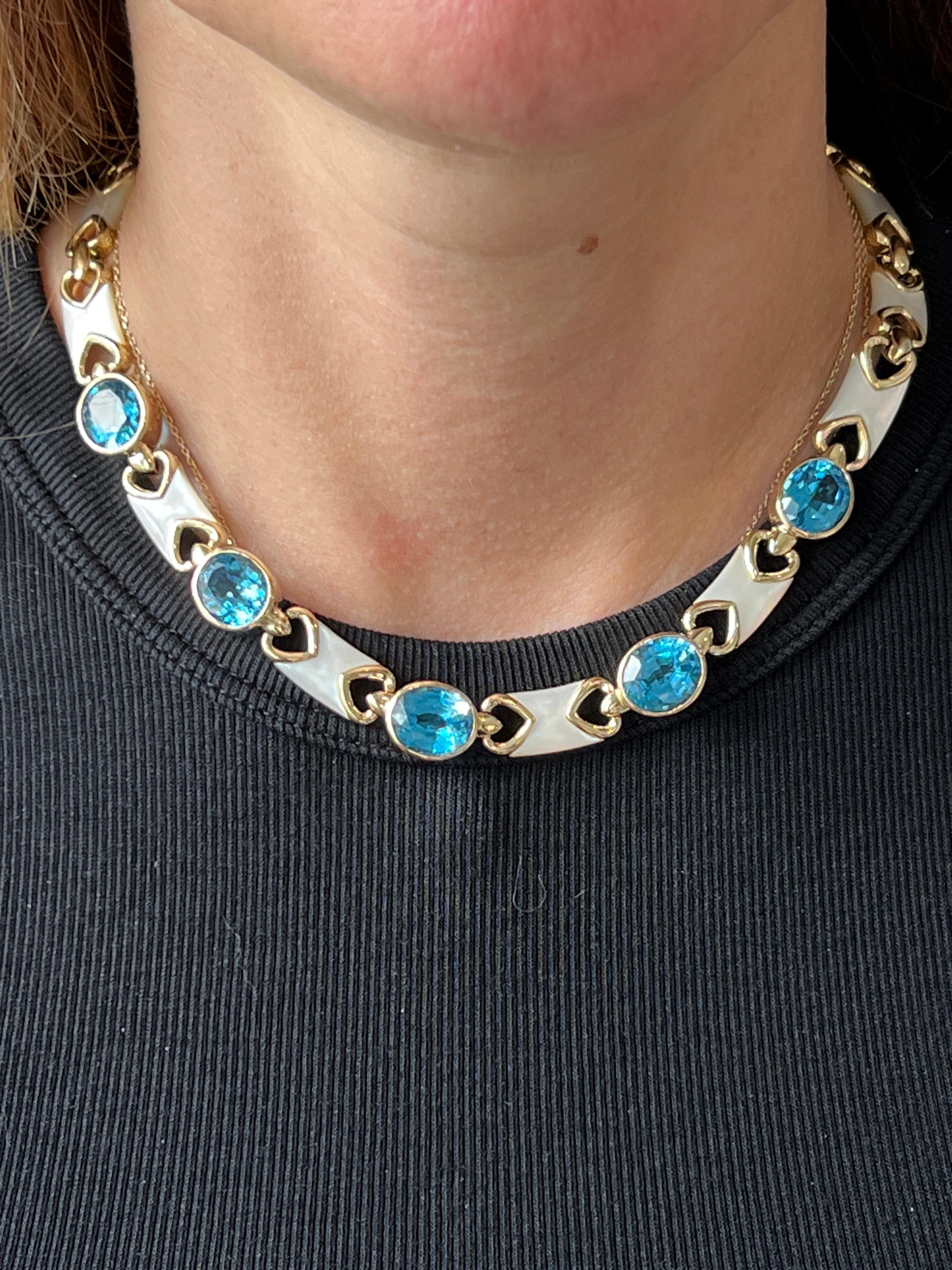 Ce superbe collier contemporain des années 1980 met en valeur l'esthétique audacieuse de l'époque grâce à l'association magistrale de topazes bleues vives et de nacres lustrées. Réalisée en or jaune 14 carats, cette pièce de 16 pouces présente cinq