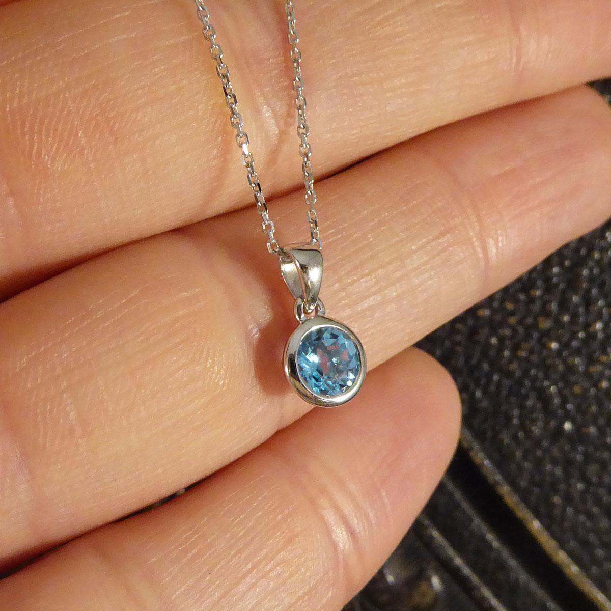 Hanging on a Contemporary 9ct White Gold Chain, sits a beautiful Blue Topaz pendant. So elegant and dainty the gorgeous Blue Topaz is Round Cut and is clean and bright. It is set in a rub over 9ct White Gold setting. It is the perfect size to be