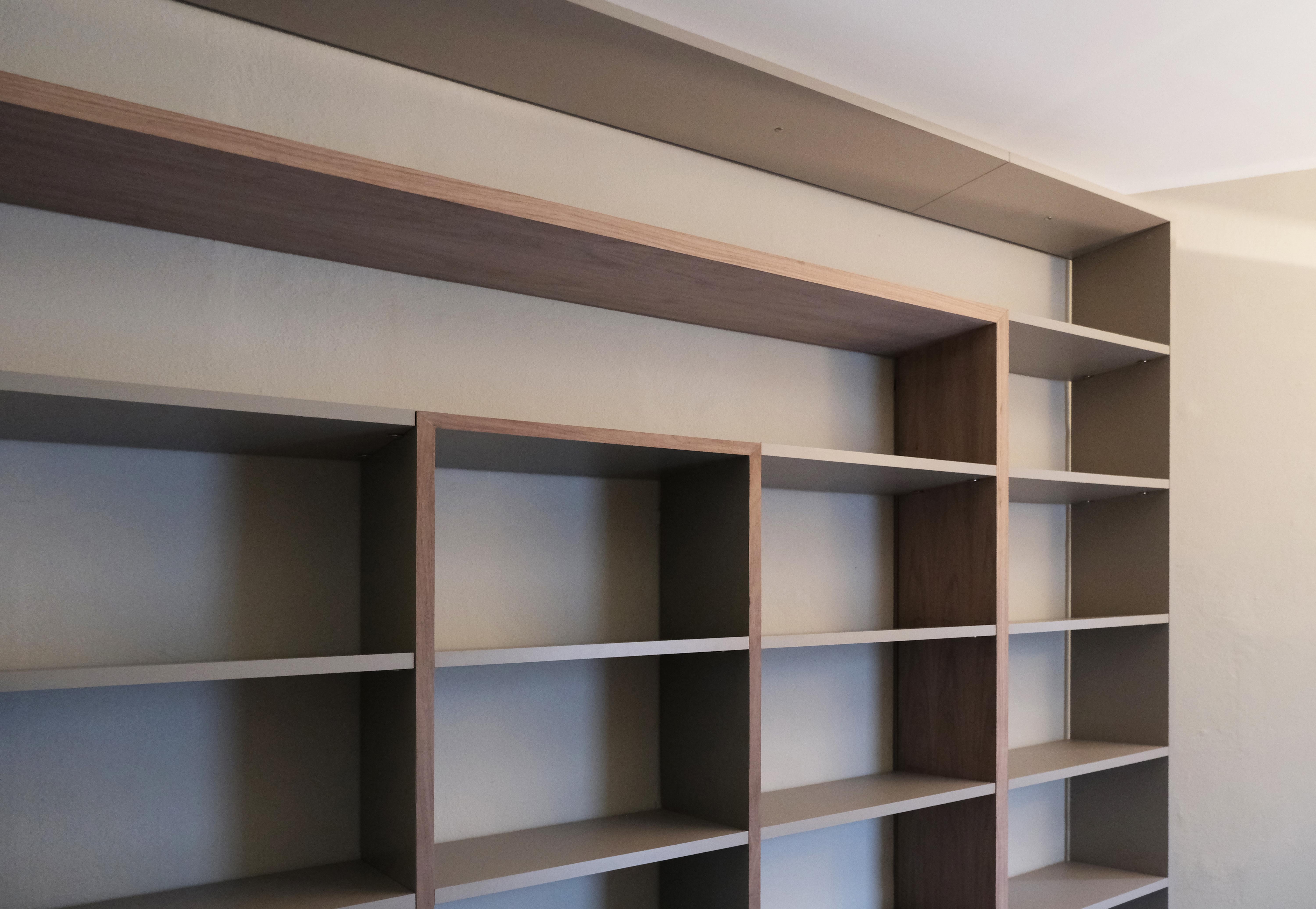 'Frame' bookcase designed by the artist Raoul Gilioli is built by excellent Italian artisans. The large suspended frame of the precious Italian walnut wood 'Canaletto' gives the bookcase a warm and natural look in contrast with the shelves in grey