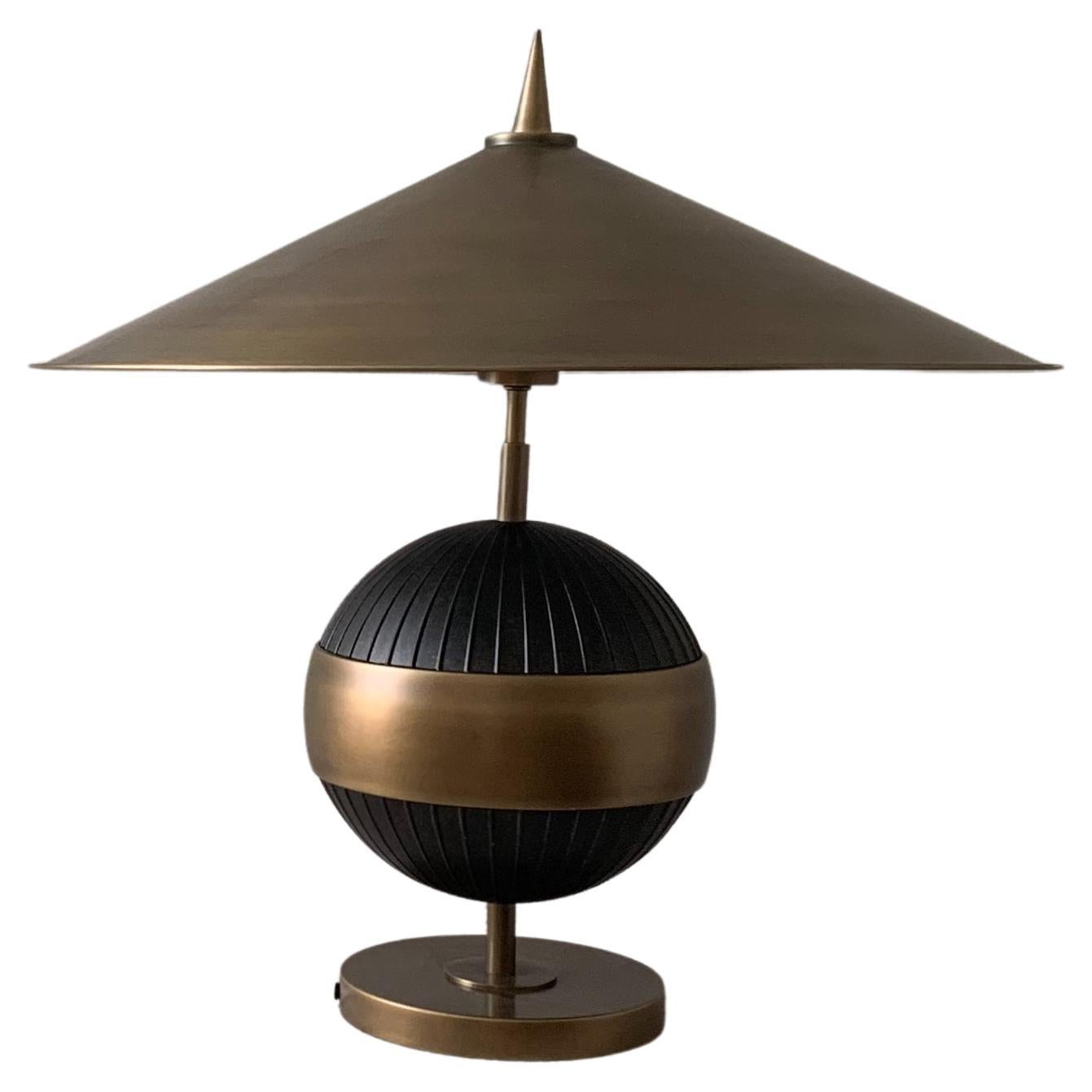 Antique brass and black “Chatta” table lamp by Currey & Company. Sculptural silhouette grounded by an oversized shade. Dimensions are taken for overall width of shade.