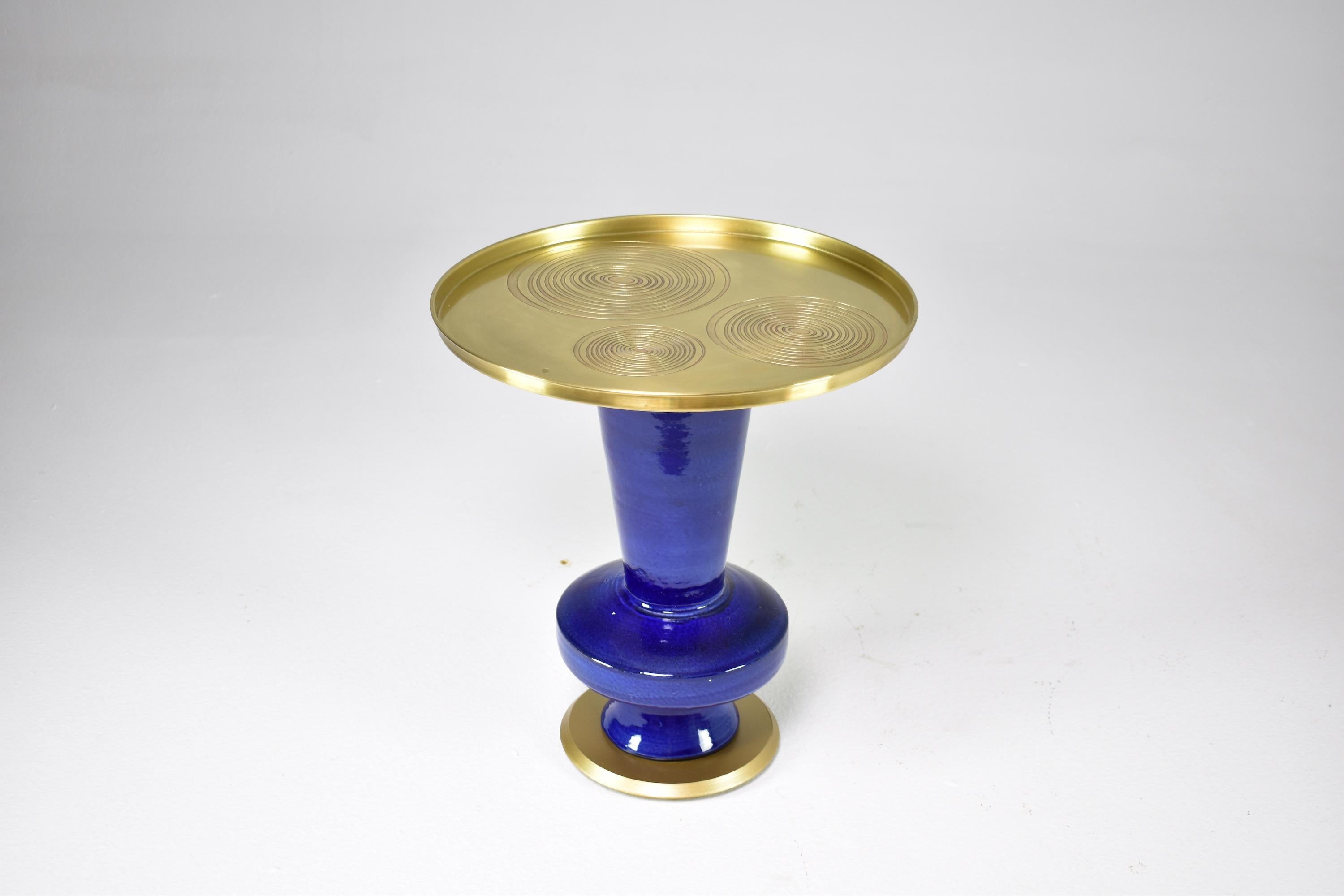 Cette table d'appoint en guéridon, unique en son genre, a été conçue par Jonathan Amar dans son atelier de Rabat. Elle se compose d'une structure en céramique émaillée bleue de forme organique et d'un plateau en laiton avec des détails circulaires