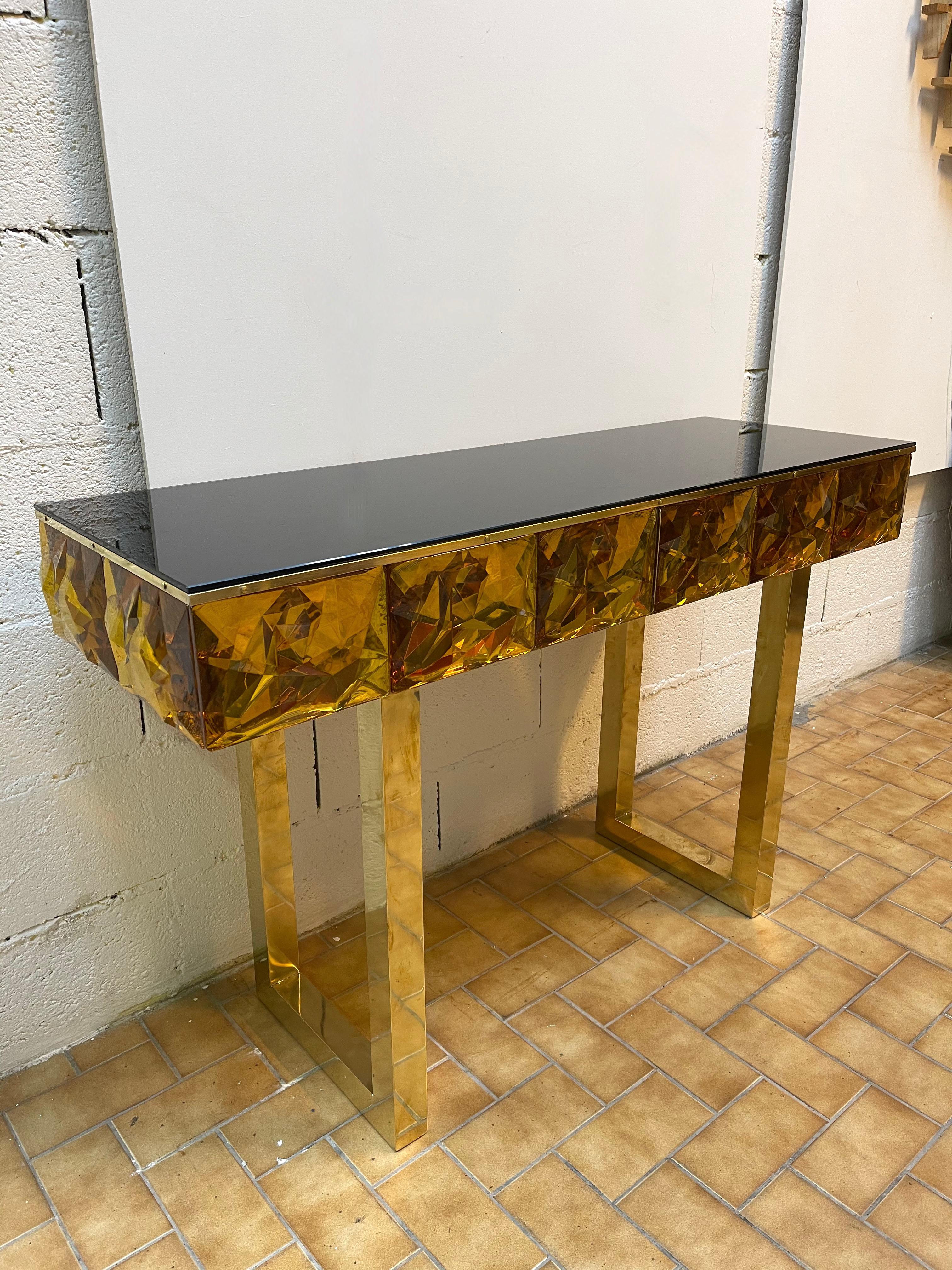 Contemporary console, full brass and large pieces of amber Murano glass with relief diamond point. Black opaline color glass top. Small artisanal workshop. The mirror same model is available.