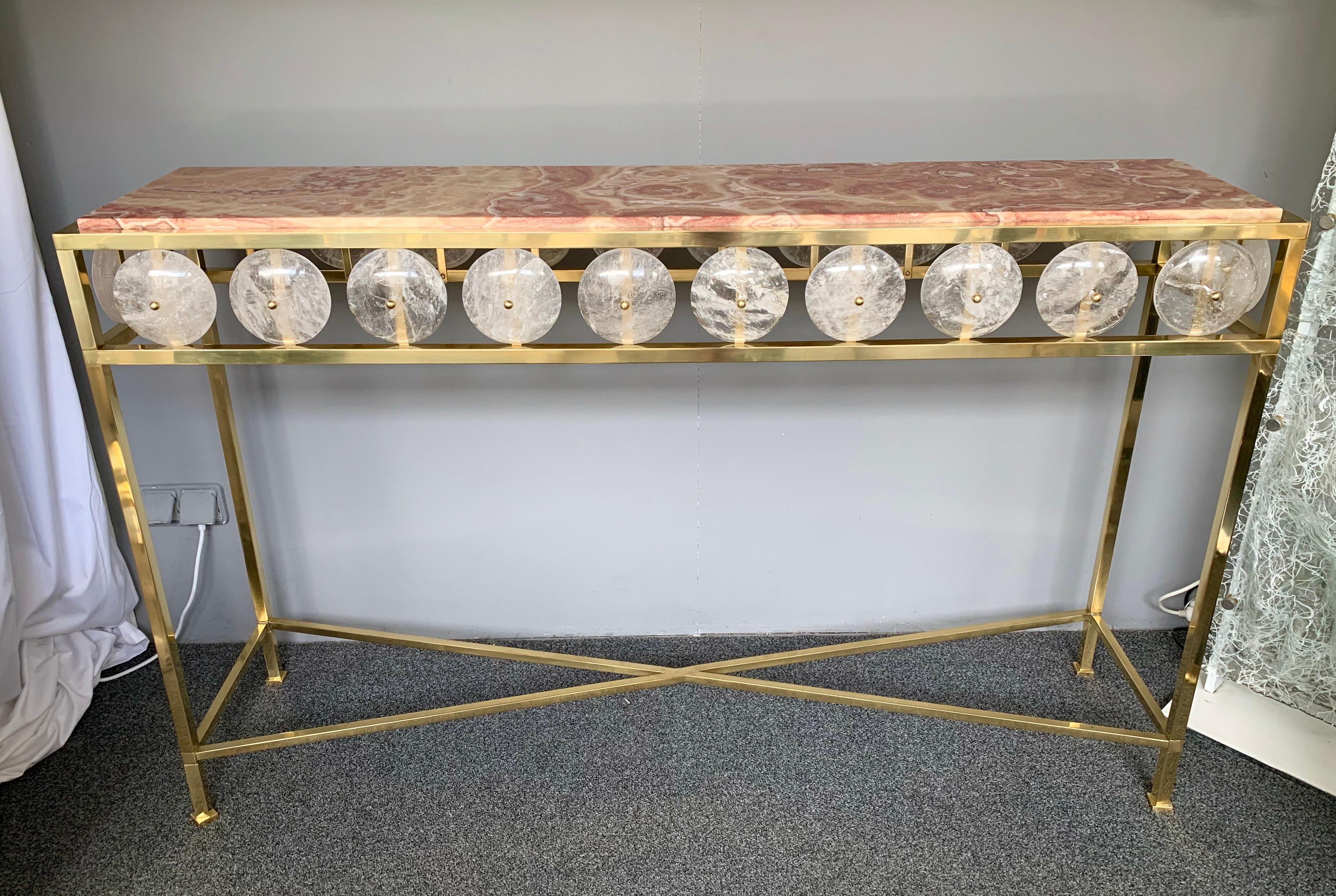 Contemporary brass console table inspired in a neoclassical Louis XVI style with large pieces of rock crystal natural stone and rare red onix top, different from marble. Small Italian workshop, few exclusive and quality production.