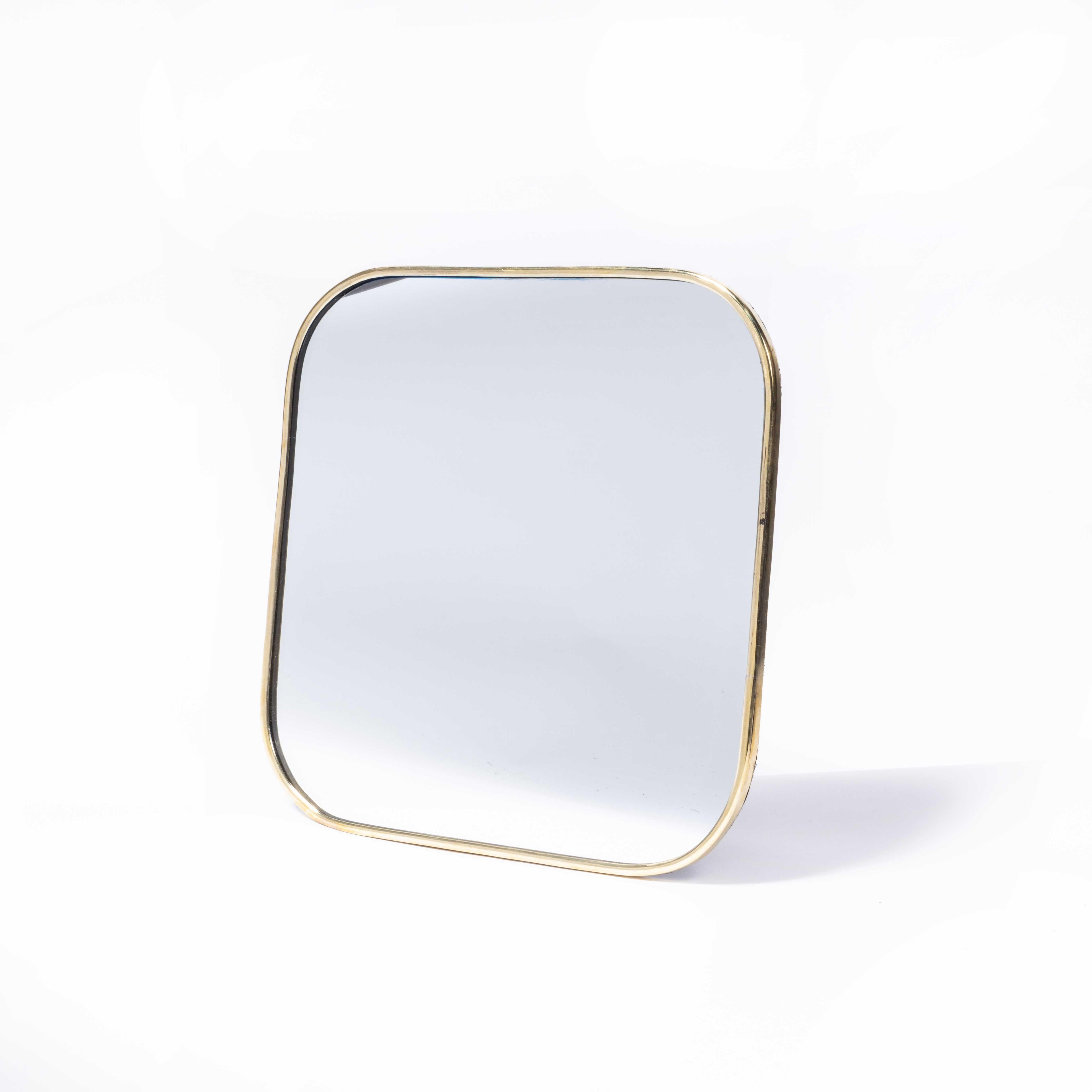 Contemporary Brass Mirror - Medium. 

Handmade for us in Morocco, a contemporary deign with a simple brass frame and textile back. The back panel has two simple eye loops for hanging, but the mirror can also just be propped up against a vertical