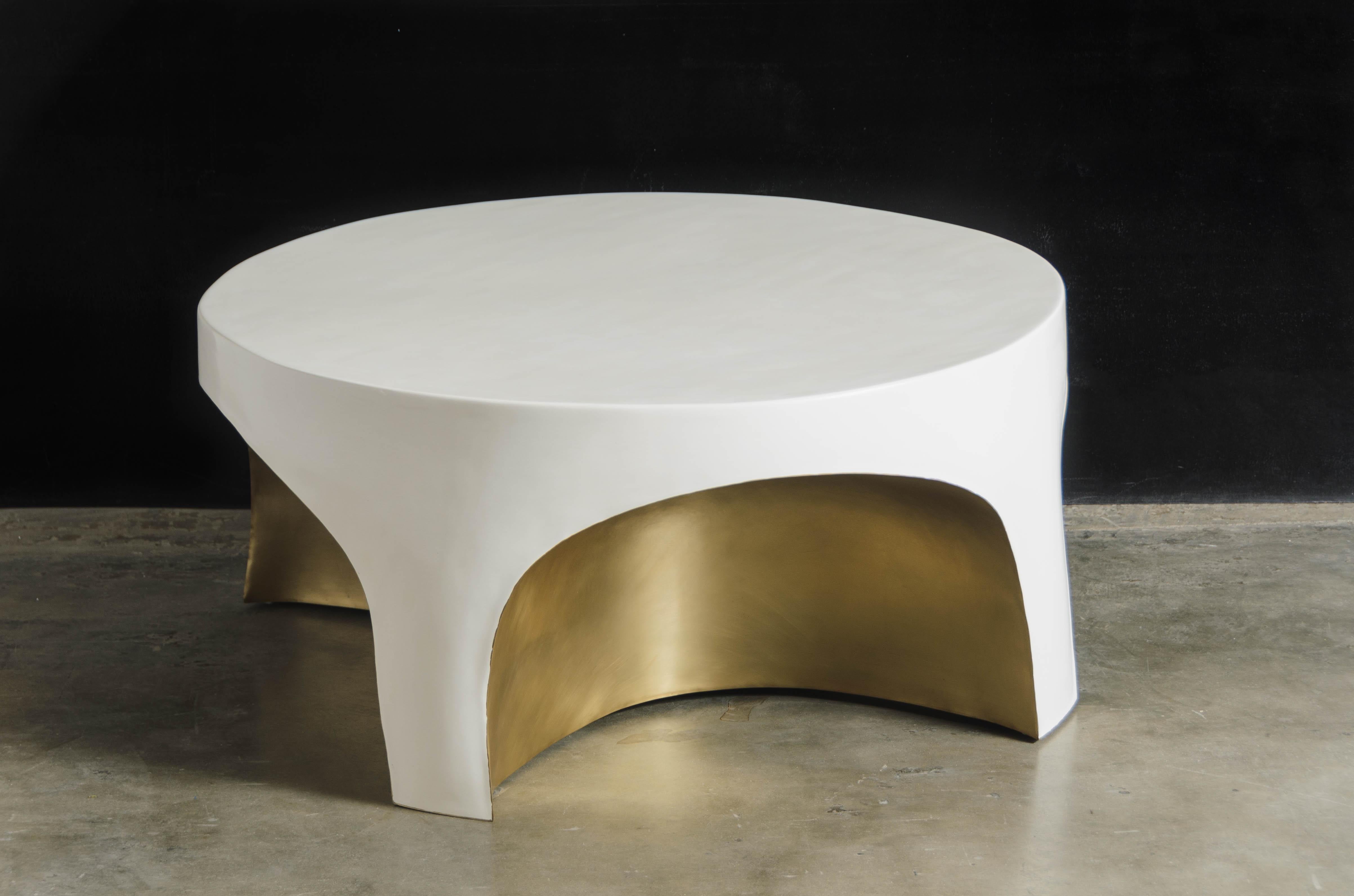 Brass rimmed curve table w/ cream lacquer.
Hand Repoussé
Antiqued Brass
Hand Made Lacquer
Contemporary 
Limited Edition

Repoussé is the traditional art of hand-hammering decorative relief onto. sheet metal. This technique involves using a