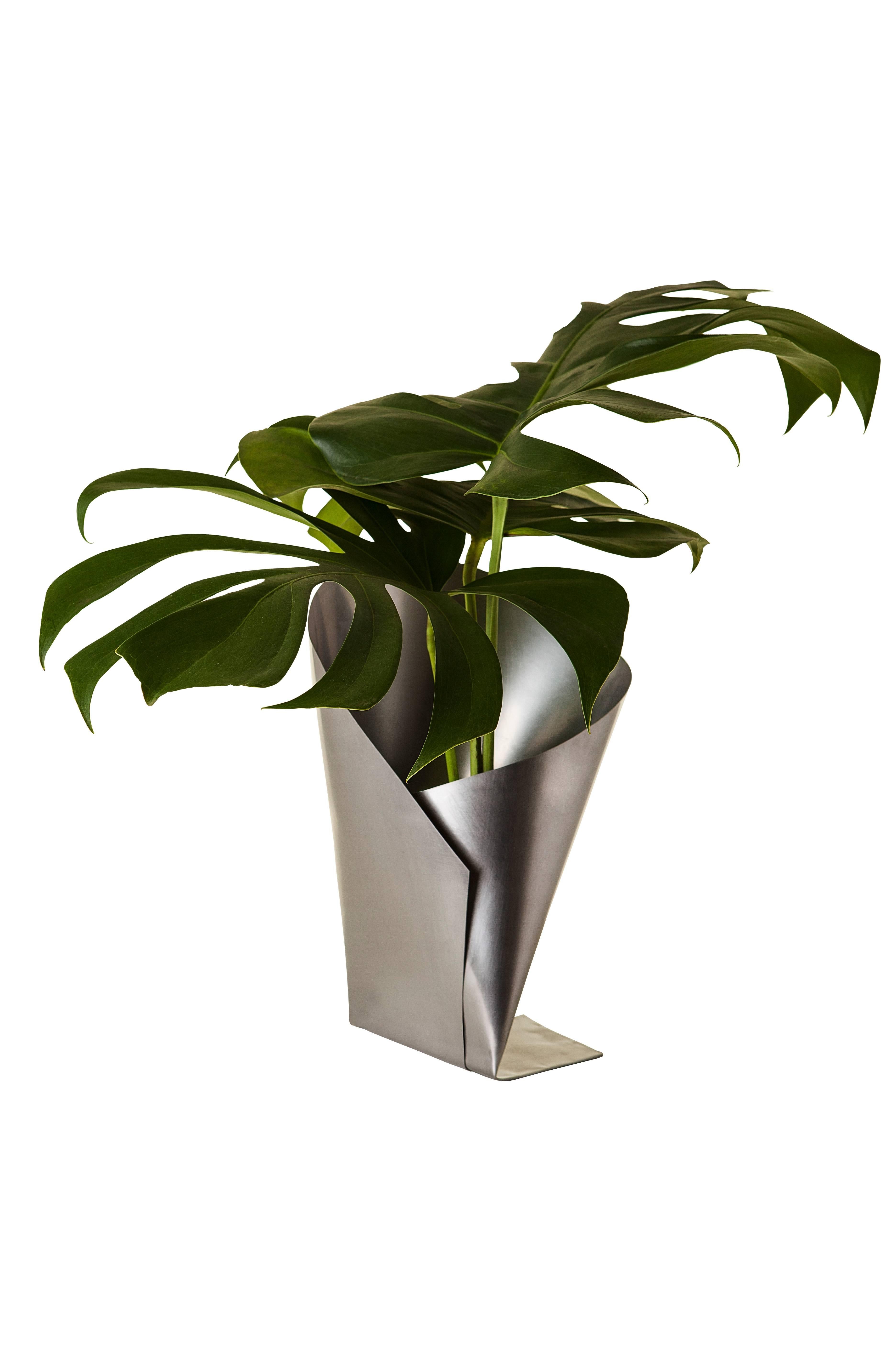 A gleaming stainless steel vase comes to life following years of material studies. The vase evolved out of an ongoing inquiry into the process of cutting and folding a single sheet of material, just like Origami. Simple without being simplistic, the