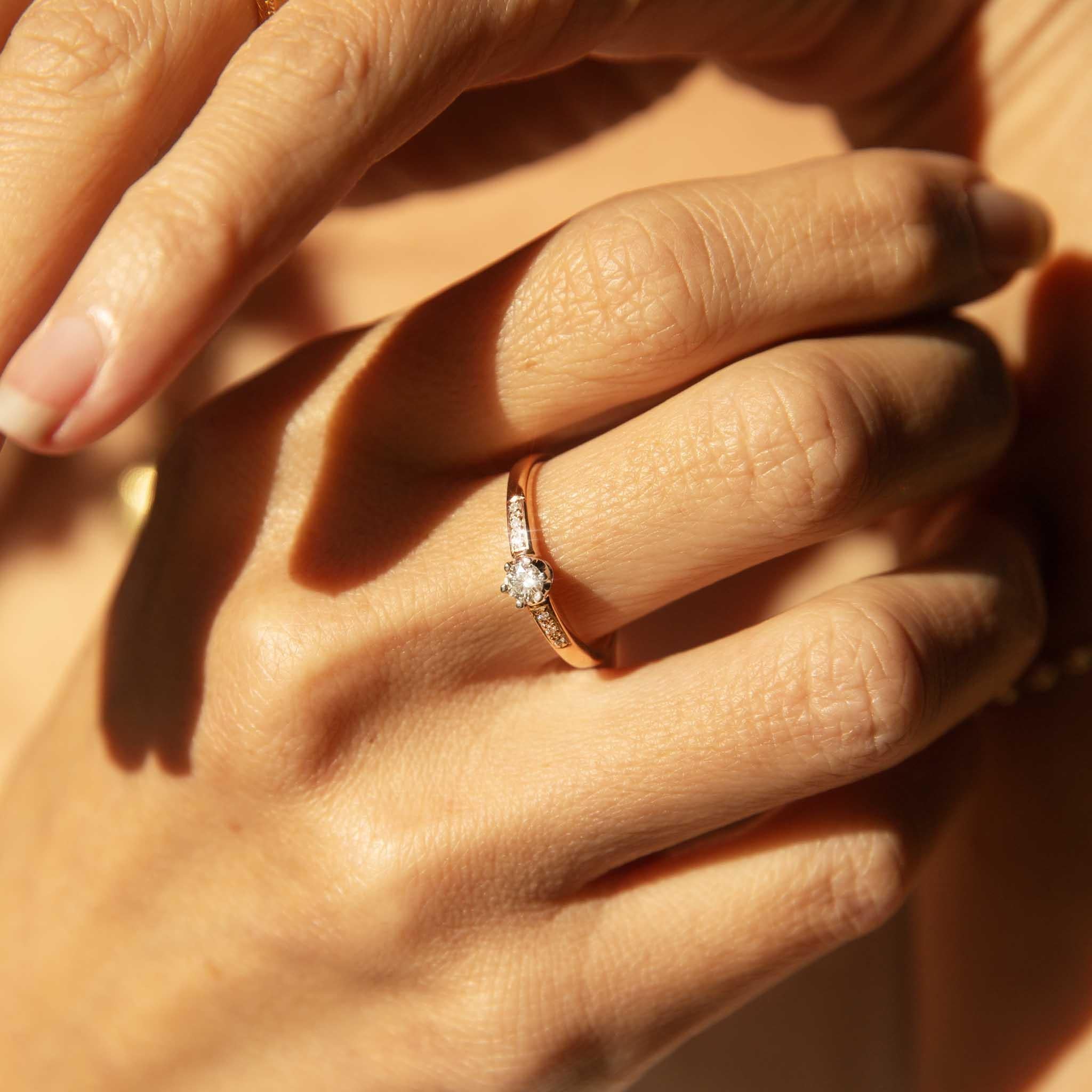 Unser Ring Coleen aus 18 Karat Roségold ist ein unvergänglicher Klassiker. Ihr funkelnder Diamant erhebt sich über einem Band, das auf beiden Seiten mit Diamanten verziert ist.  Eine süße Art und Weise, Versprechen zu geben, die dein Herz halten