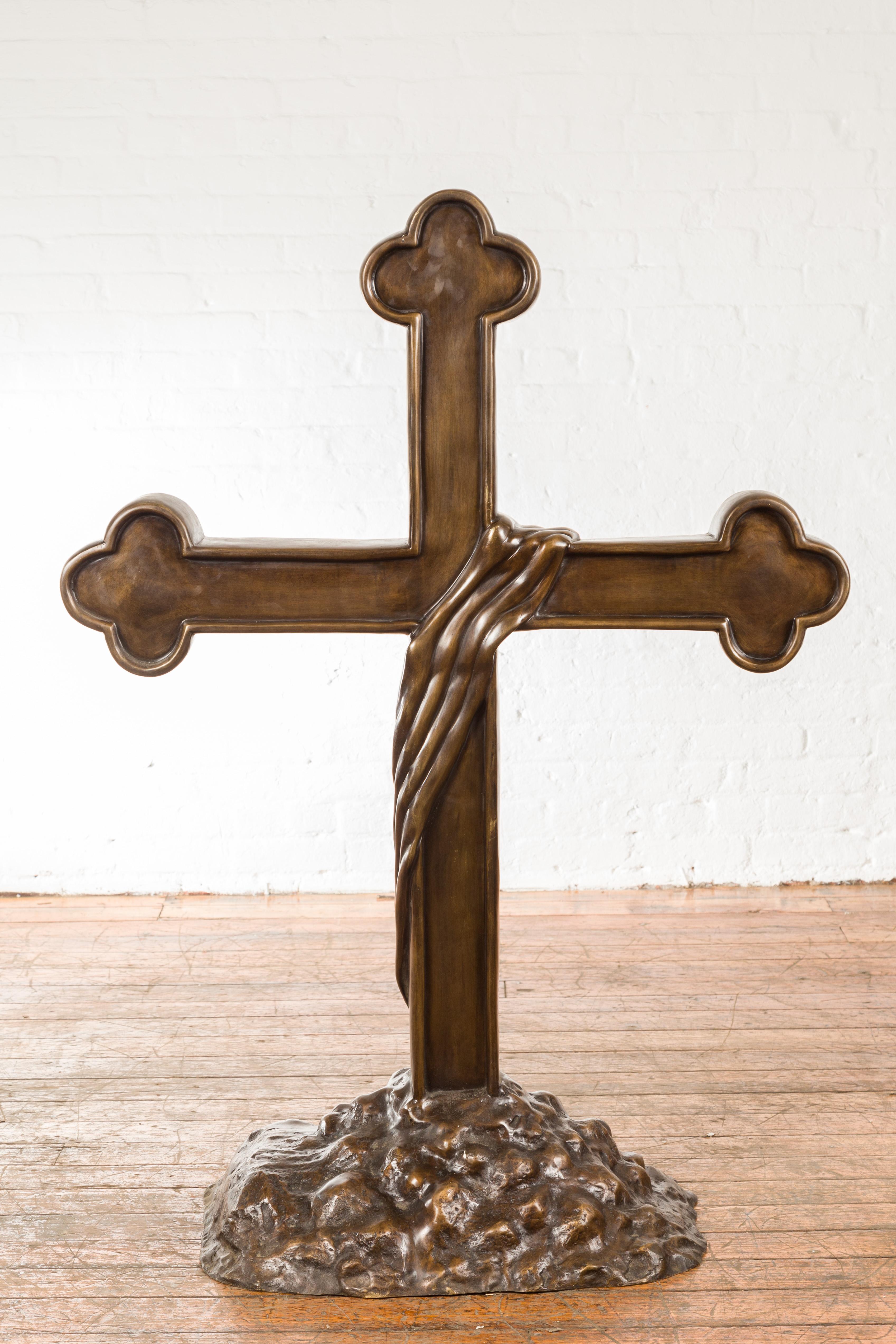 Croix religieuse contemporaine en bronze à cire perdue, aux extrémités triplées et à la base rocheuse. Créée avec la technique traditionnelle de la cire perdue (à la cire Perdue) qui permet une grande précision et finesse dans les détails, cette