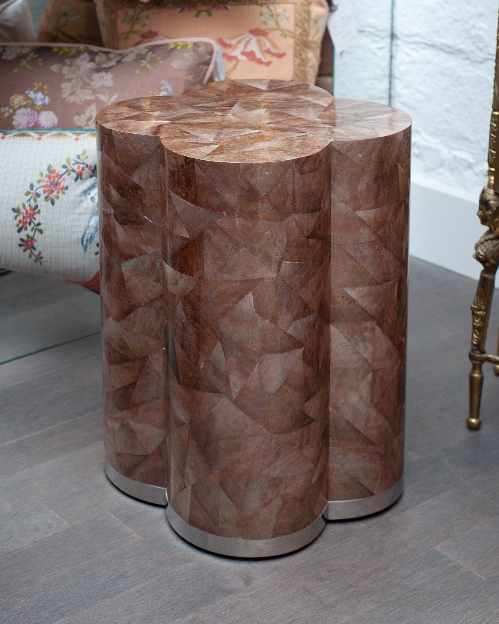 A stunning contemporary clover drum table finished in golden brown pen shell with polished stainless steel trim at the base. Masterfully created and flawlessly executed, this shell drum table boasts a rainbow of tones dispersed amongst the brown pen